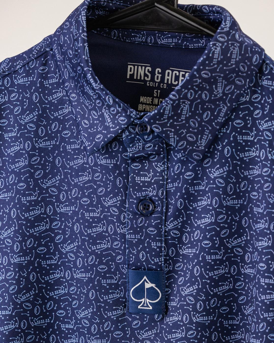 Youth Playmaker golf shirt featuring a navy blue pattern with playful graphics, designed for young golfers to stand out.