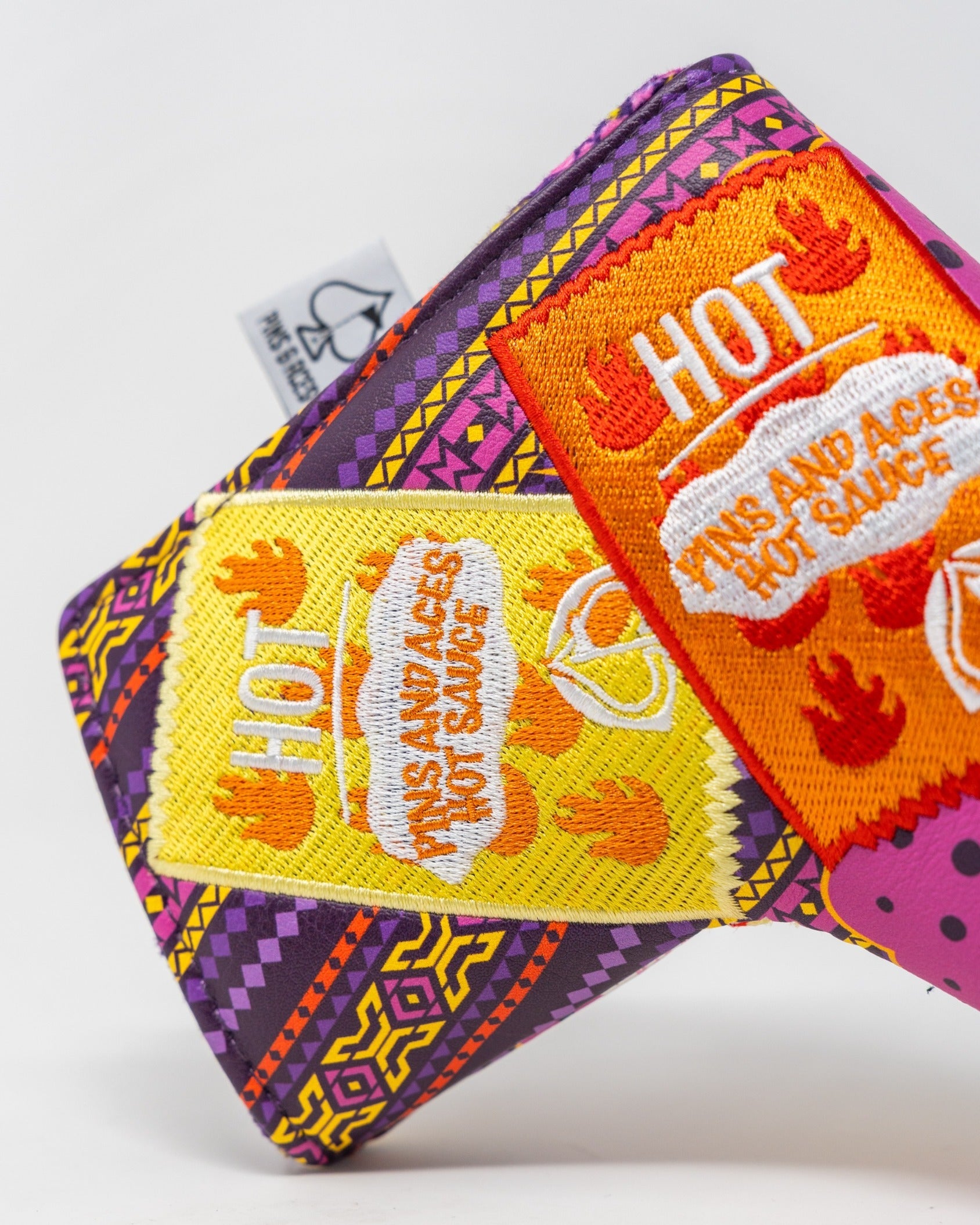 Bold blade putter cover featuring vibrant patterns and playful hot sauce graphics for a standout golf accessory.