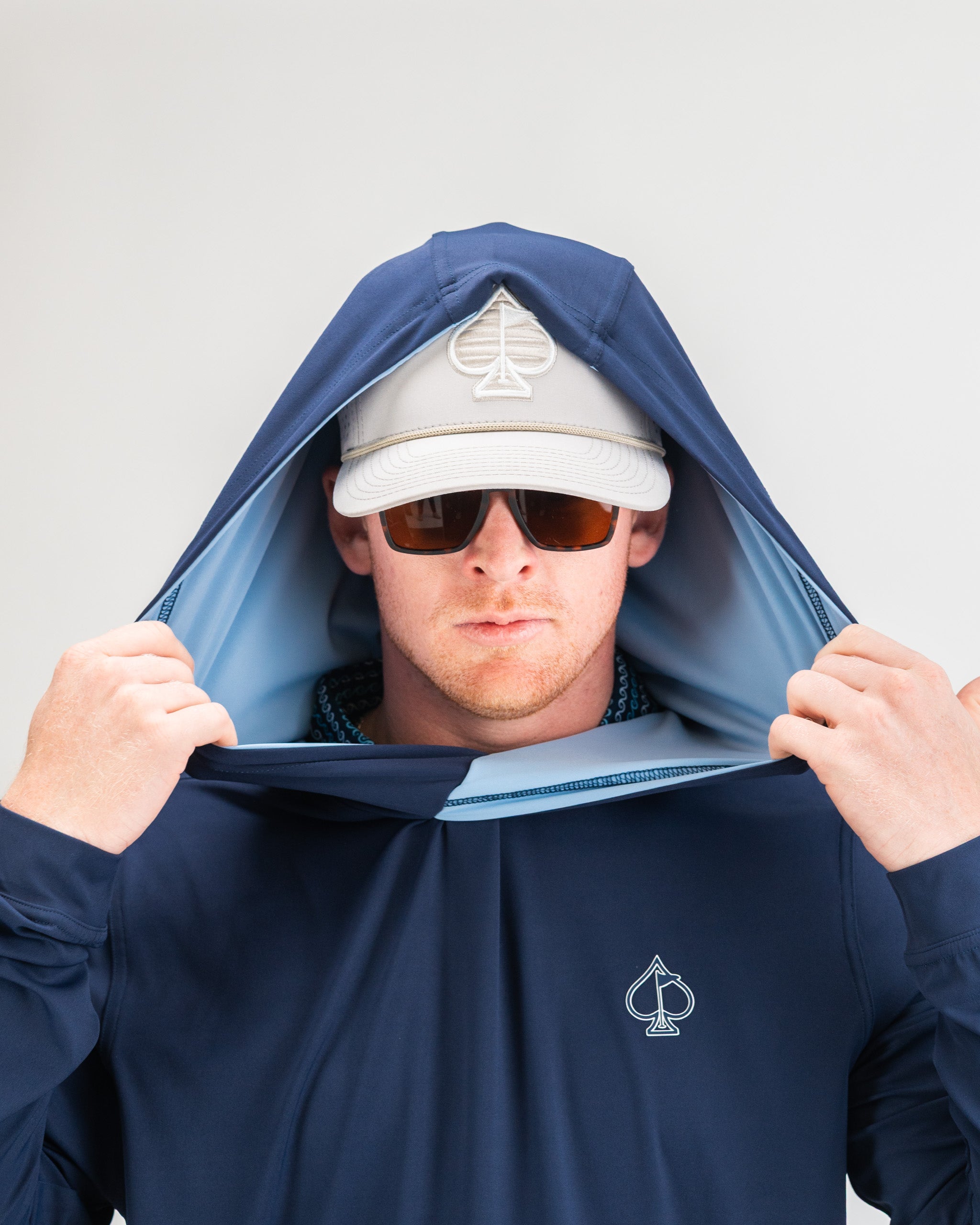 Navy performance golf hoodie with a hood, worn by a man in sunglasses and a cap, showcasing a stylish design.