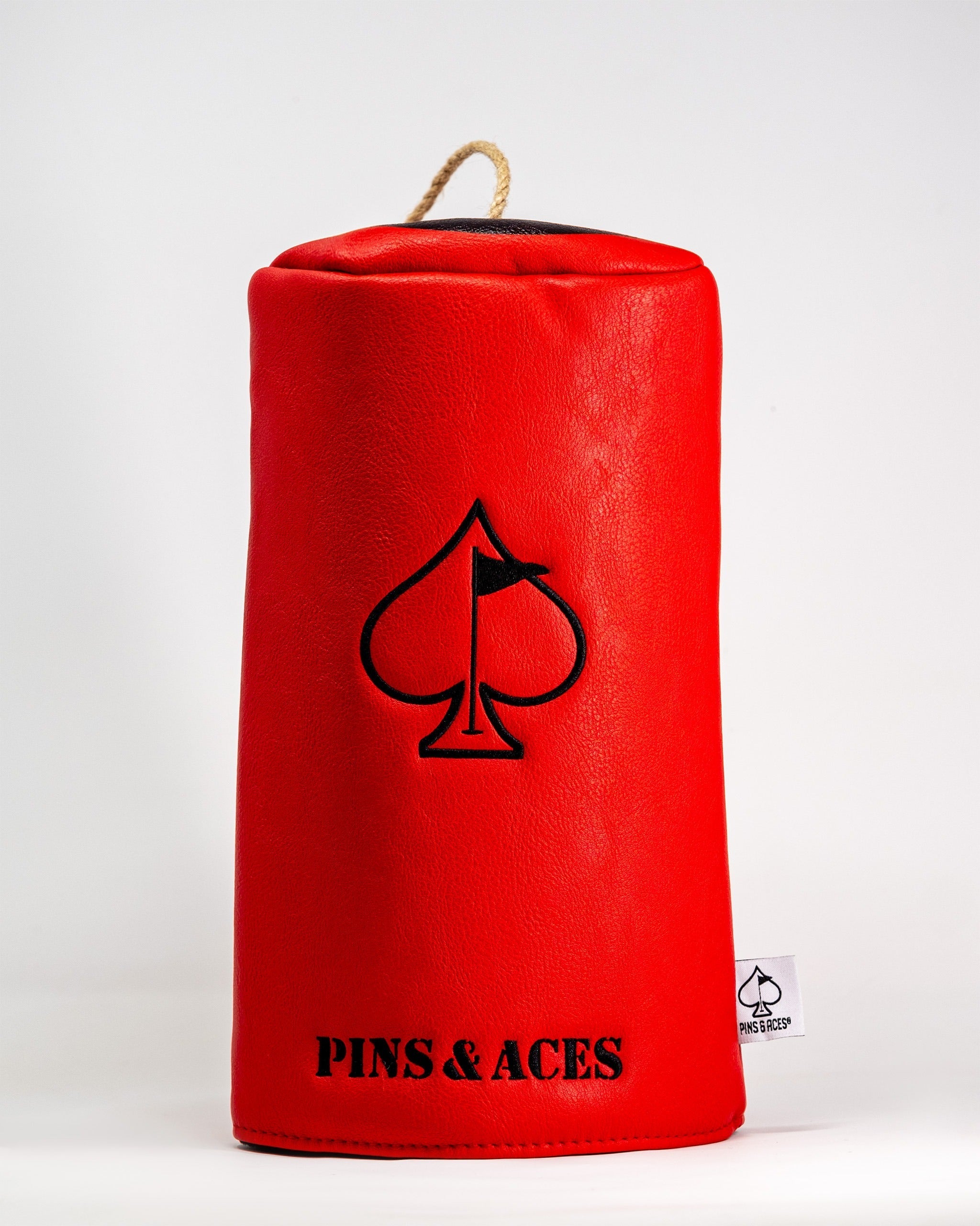 Bold red driver cover featuring a black spade logo and "Pins & Aces" branding, designed for stylish golfers.