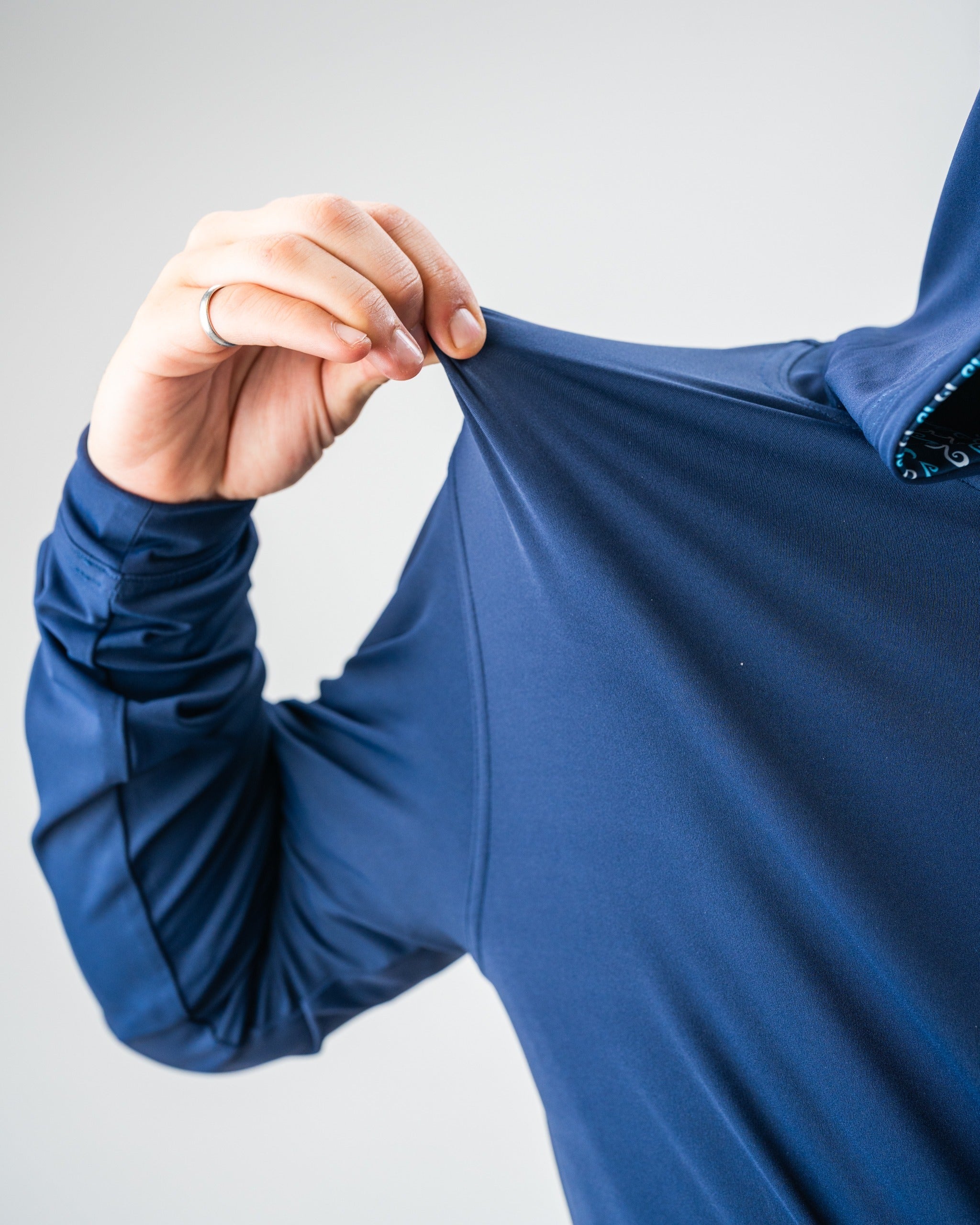 Close-up of a person pulling stretchable, vibrant blue golf apparel fabric to show its flexibility and bold color.