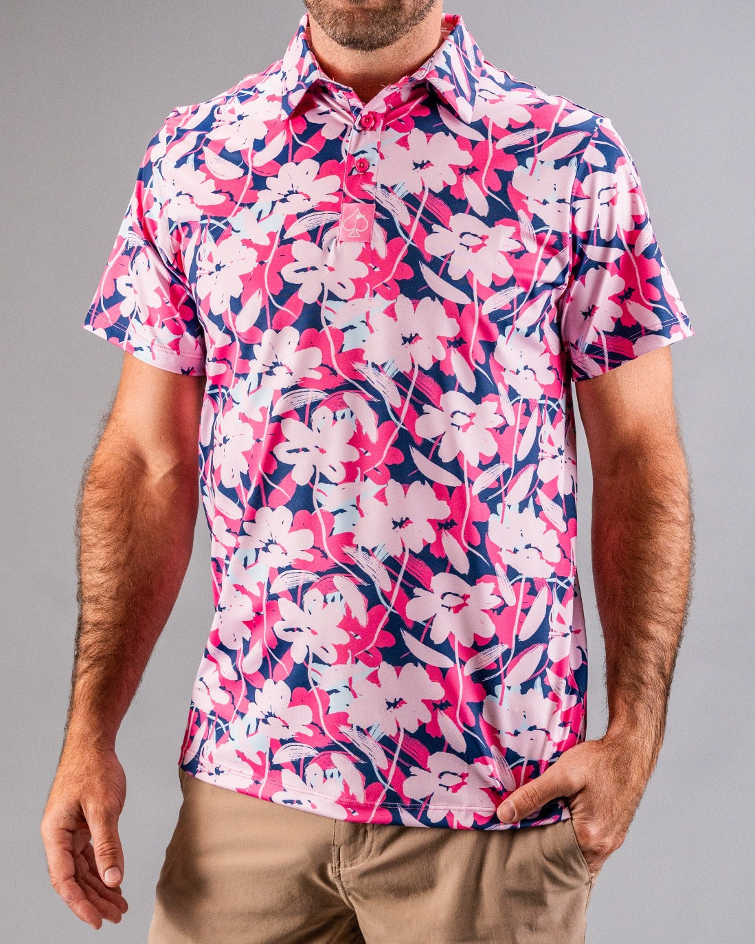 Bright pink, navy, and white floral golf shirt with bold pattern, short sleeves, and classic collar for standout style.