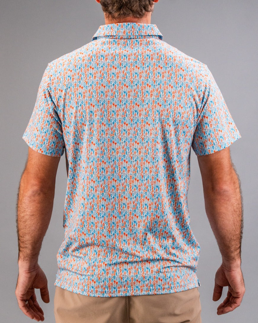 Colorful patterned golf shirt with small orange and blue abstract designs, short sleeves, and a button-up collar.