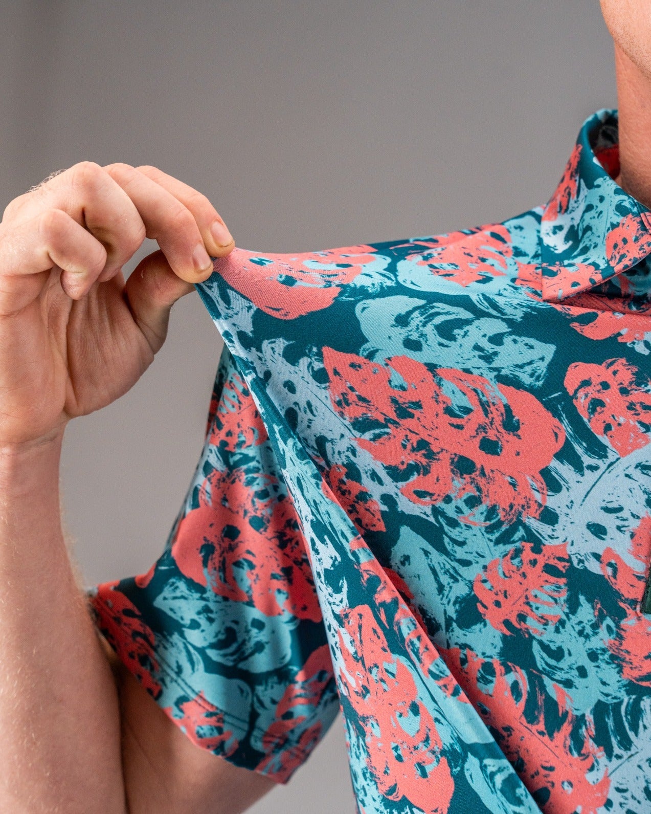 Close-up of a colorful, floral-patterned golf shirt in teal, coral, and black, highlighting bold, unique golf apparel for ...