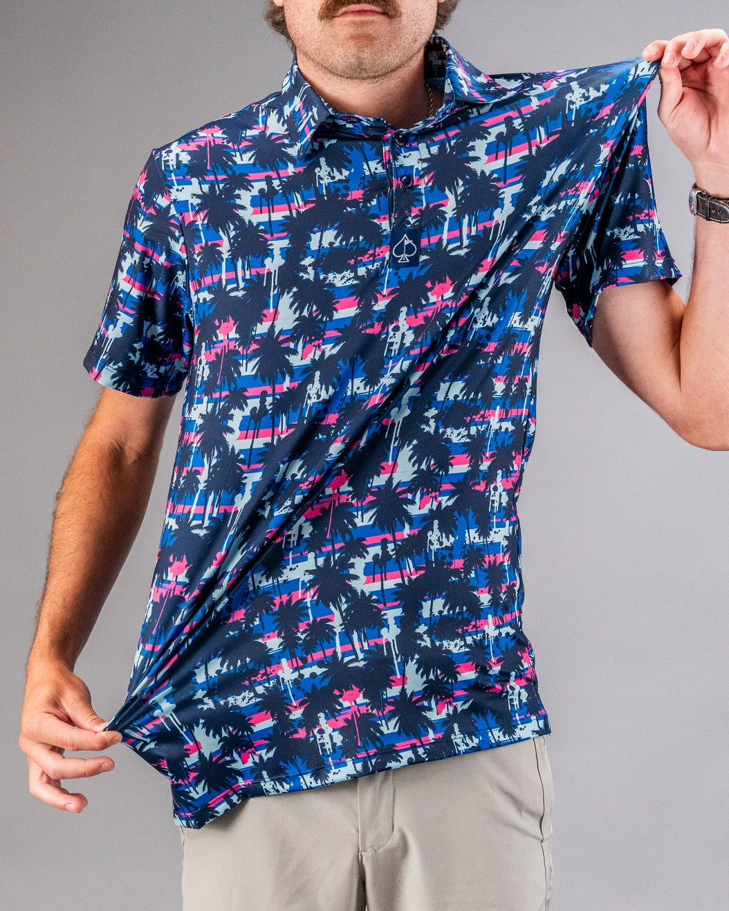 Bright blue, pink, and black tropical golf shirt with palm tree and stripe pattern, perfect for standing out on the course.