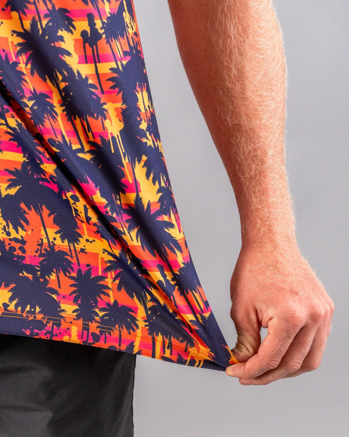 Close-up of a golfer's colorful, tropical palm tree patterned shirt in vibrant orange, pink, yellow, and navy.