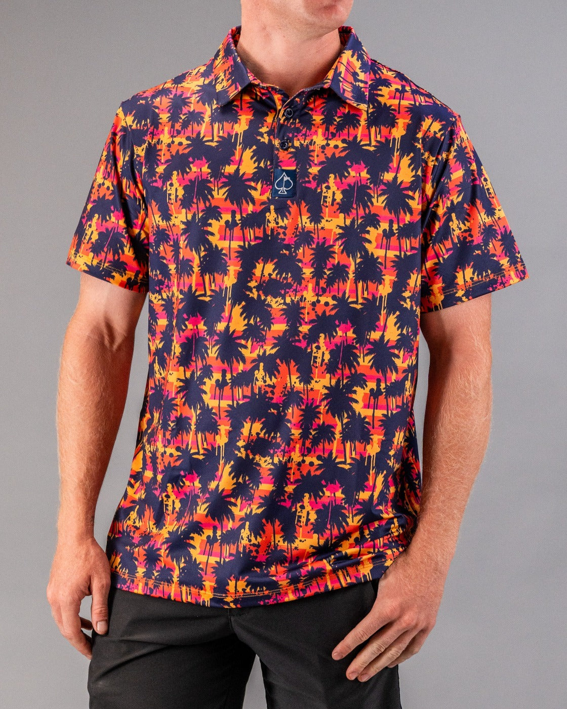 Bright tropical palm tree print golf shirt in pink, orange, and navy for bold on-course style.