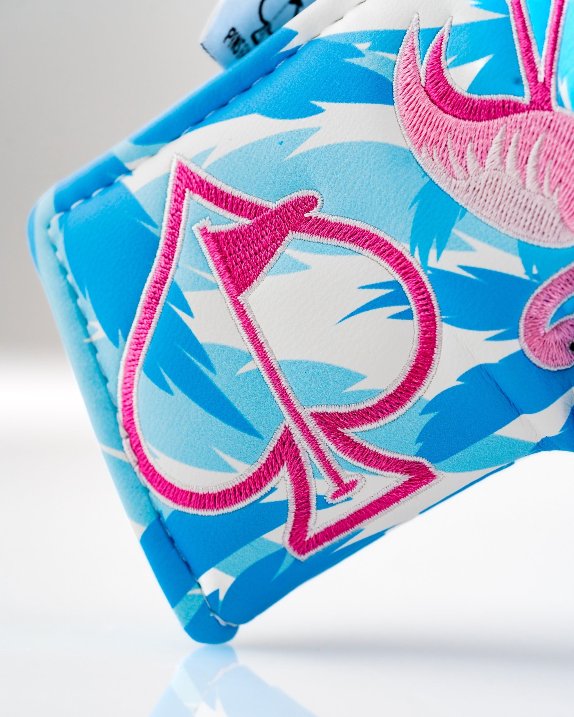 Bright blue blade putter cover featuring a flamingo design and pink spade emblem, perfect for stylish golfers.