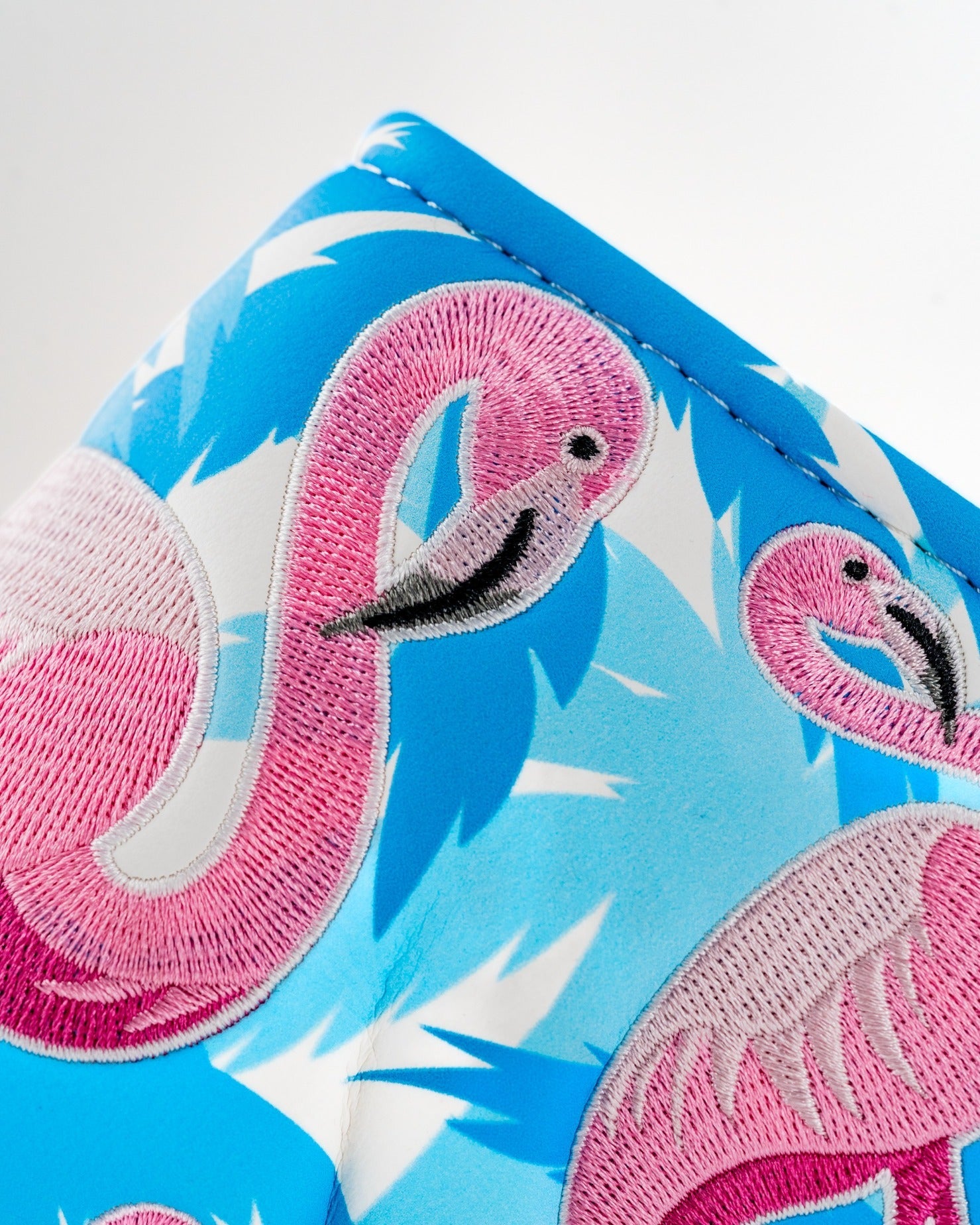 Bright blue blade putter cover featuring vibrant pink flamingo embroidery, perfect for golfers seeking a fun style.