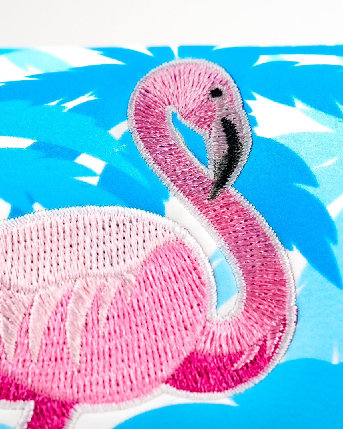 Bright pink flamingo embroidered on a vibrant blue background, featured on a mallet putter cover for golfers.