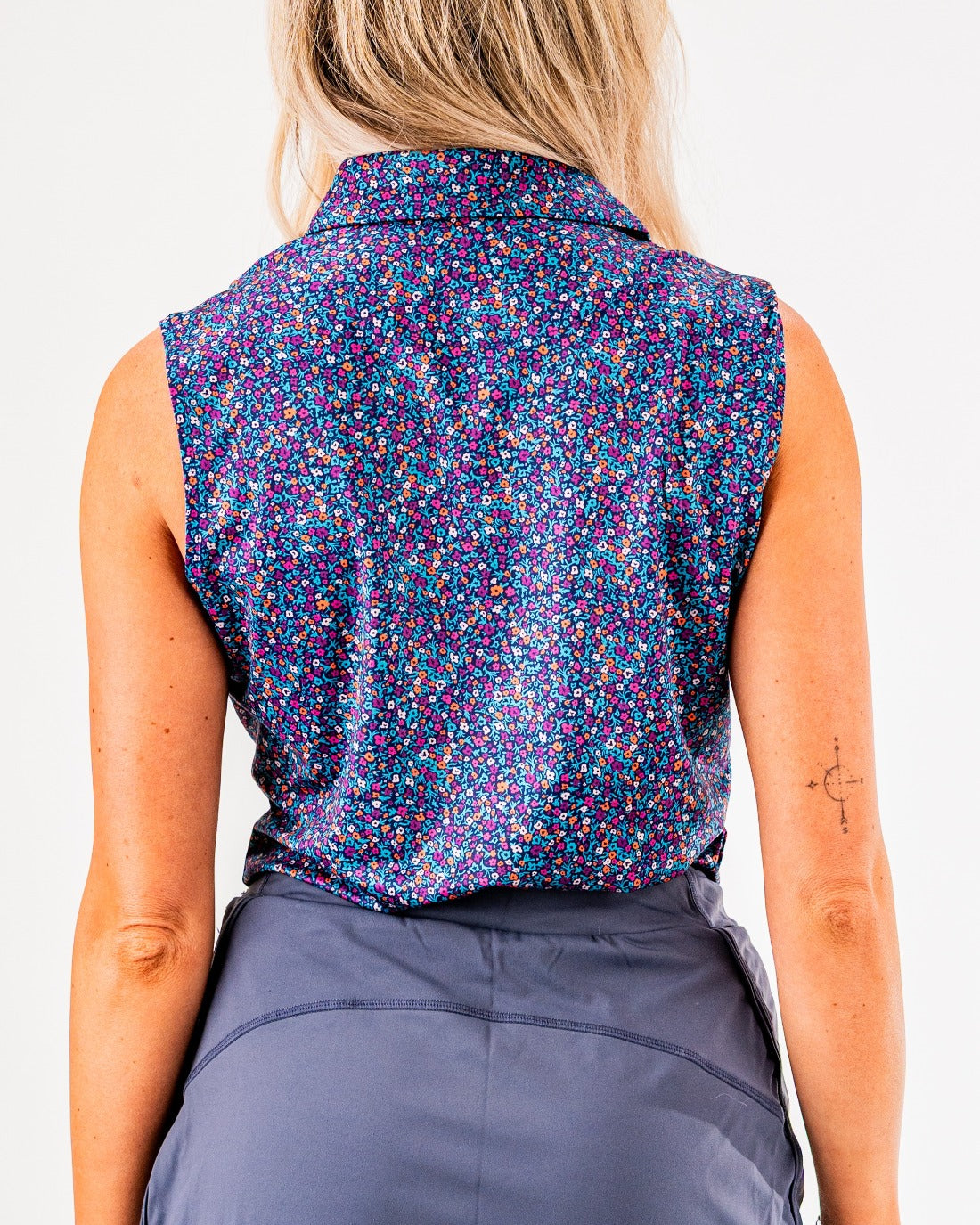 Women's sleeveless lavender floral golf shirt featuring a vibrant pattern, perfect for stylish performance on the course.