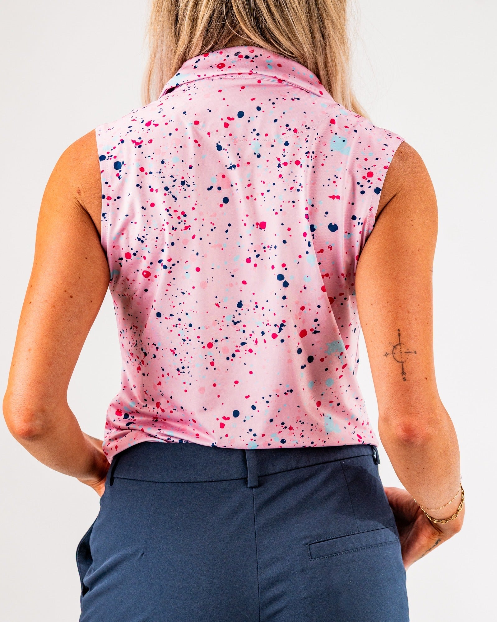 Women's pink sleeveless golf top featuring a vibrant splatter design, perfect for stylish performance on the course.