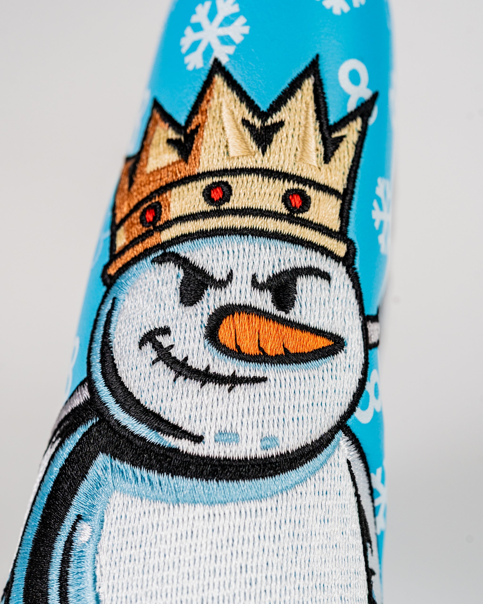 Bright blue blade putter cover featuring a crowned snowman design, perfect for adding a festive touch to your golf game.