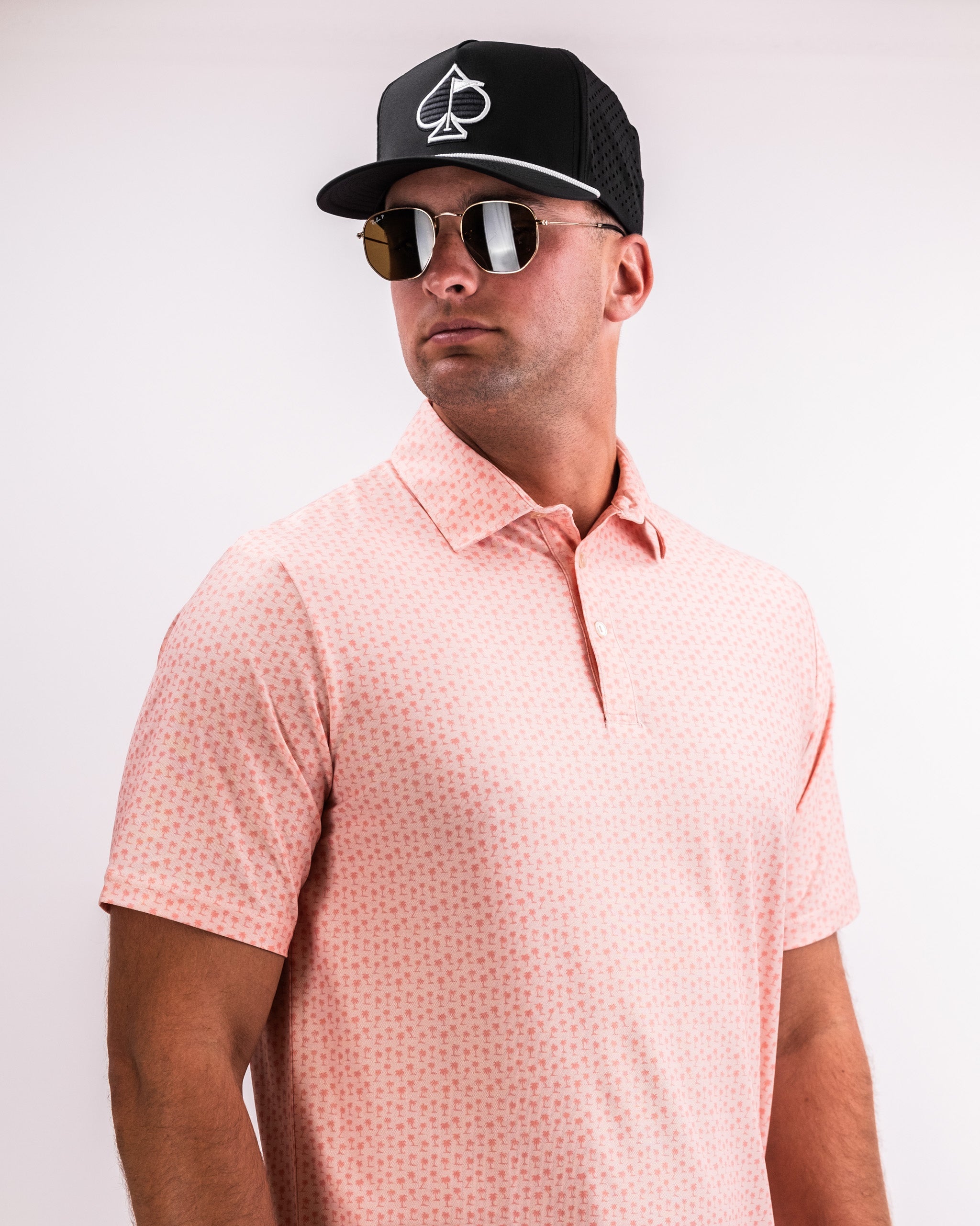Player Preferred™ Polo in Coral Palms featuring a vibrant coral color with palm leaf patterns, displayed on a neutral background.