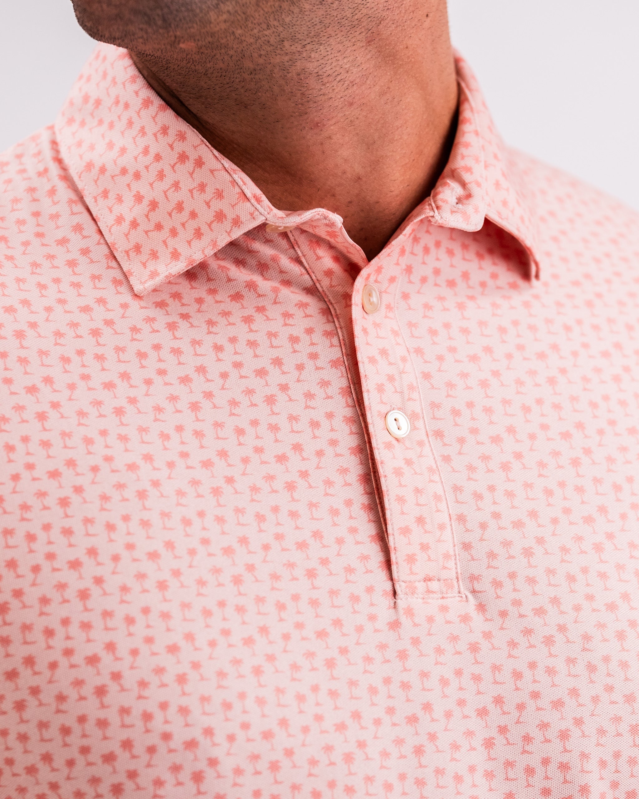 Player Preferred™ Polo in Coral Palms featuring a vibrant palm print design, short sleeves, and a classic collar. Perfect for casual wear or outdoor activities.