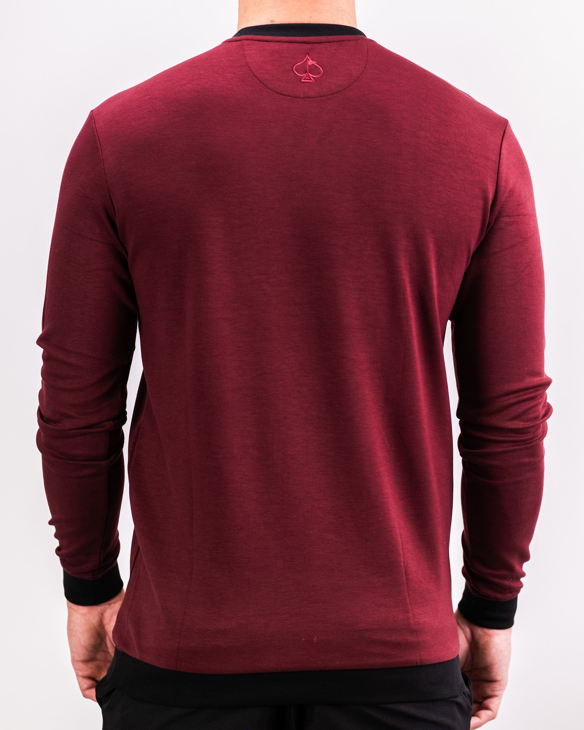 Back view of a man wearing a maroon Player Preferred™ Crewneck sweatshirt with black cuffs and neckline, featuring a subtle embroidered spade logo.