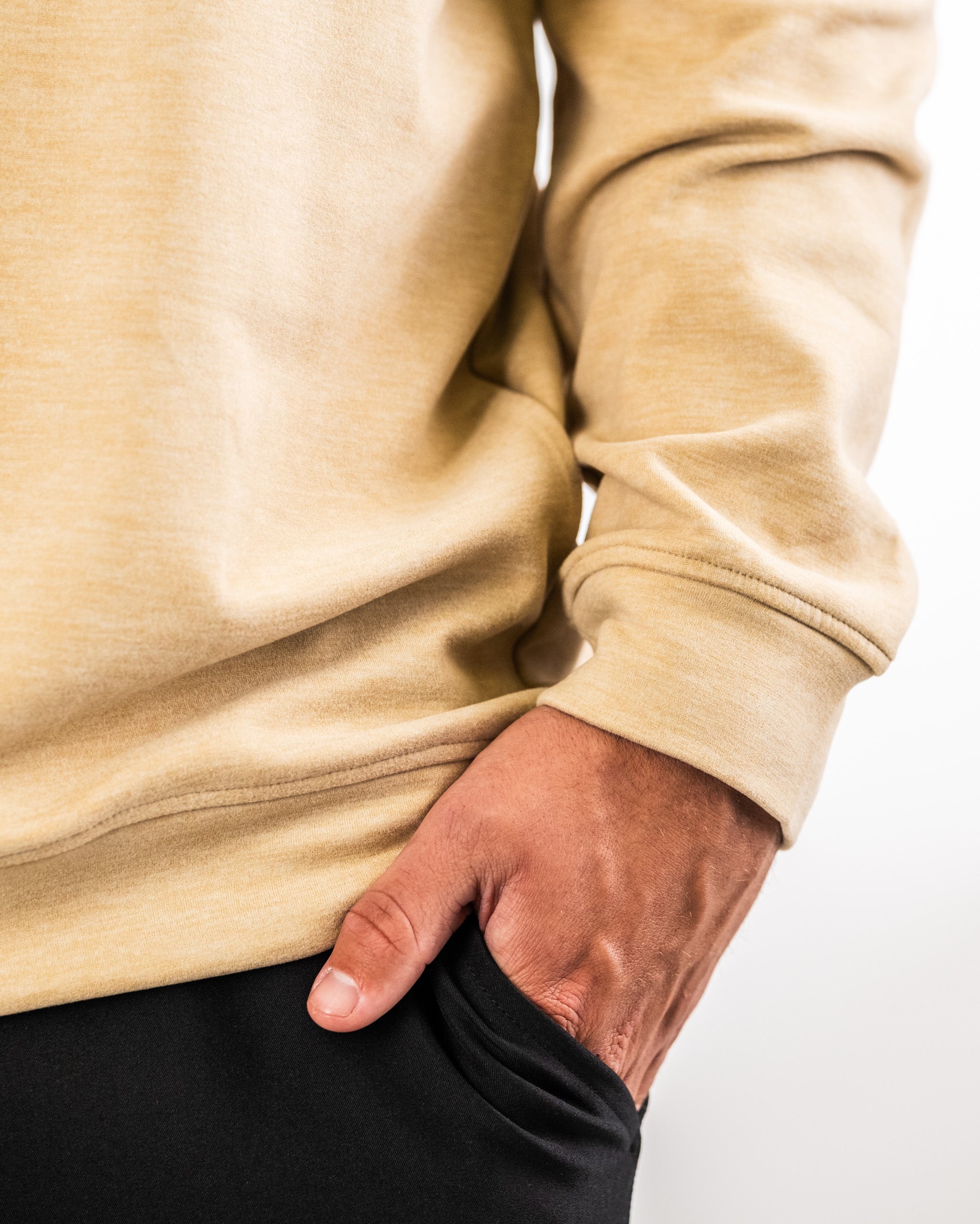 Close-up of a person wearing a beige Player Preferred™ Pullover in sand color, with hand in pocket, showcasing casual style and fabric texture.