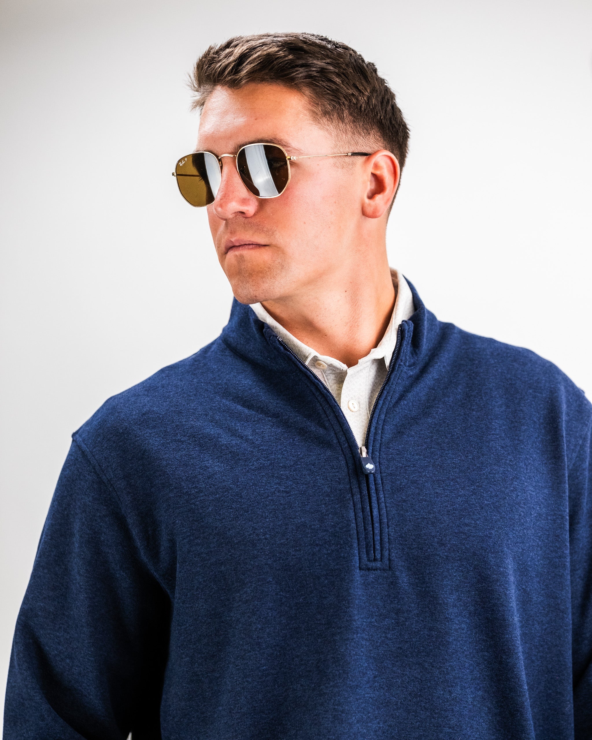 Man wearing a navy Heathered Player Preferred™ Pullover with sunglasses, looking to the side against a plain background.