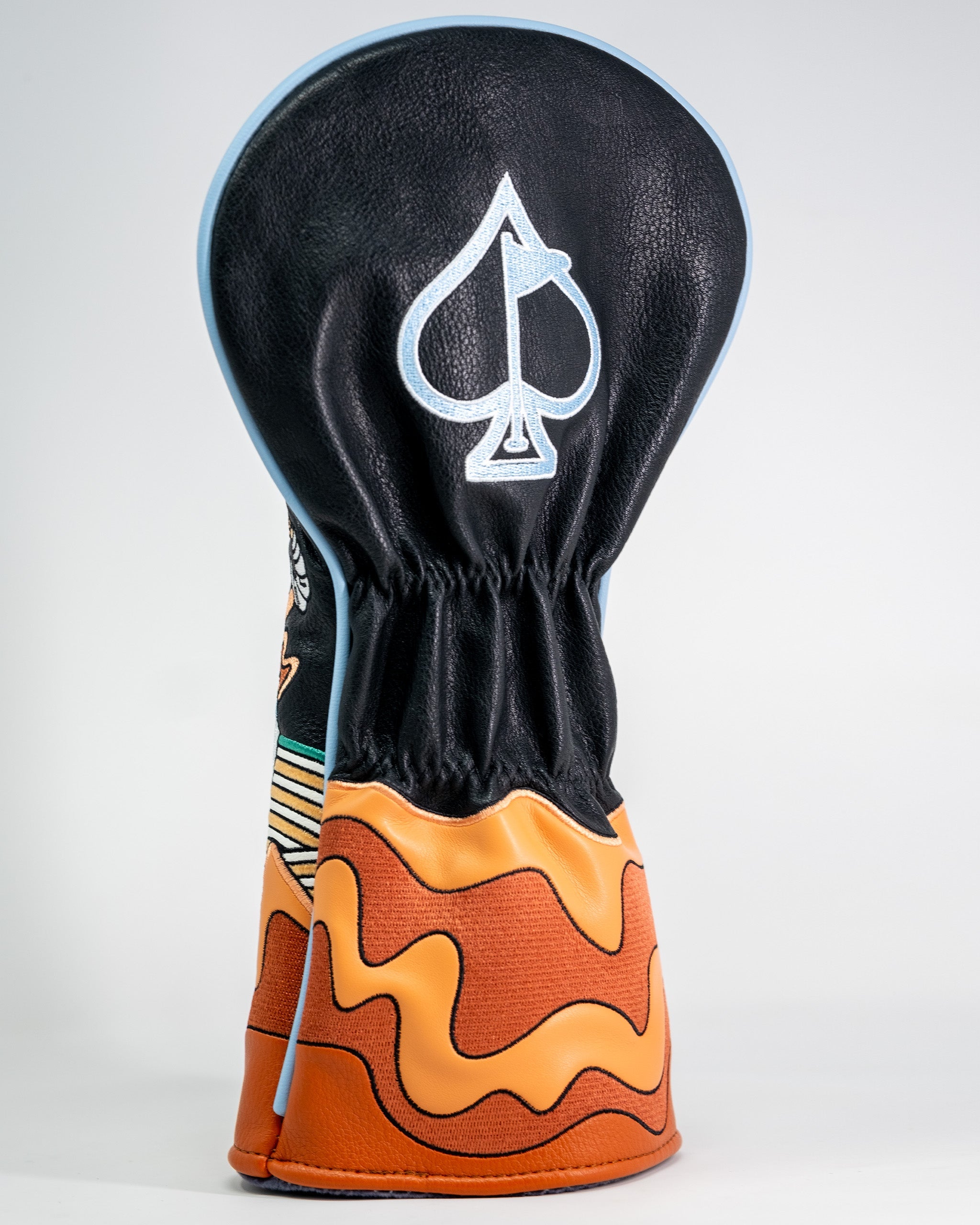 Golf driver headcover featuring a black top with a white spade logo and a colorful orange and black patterned lower section.