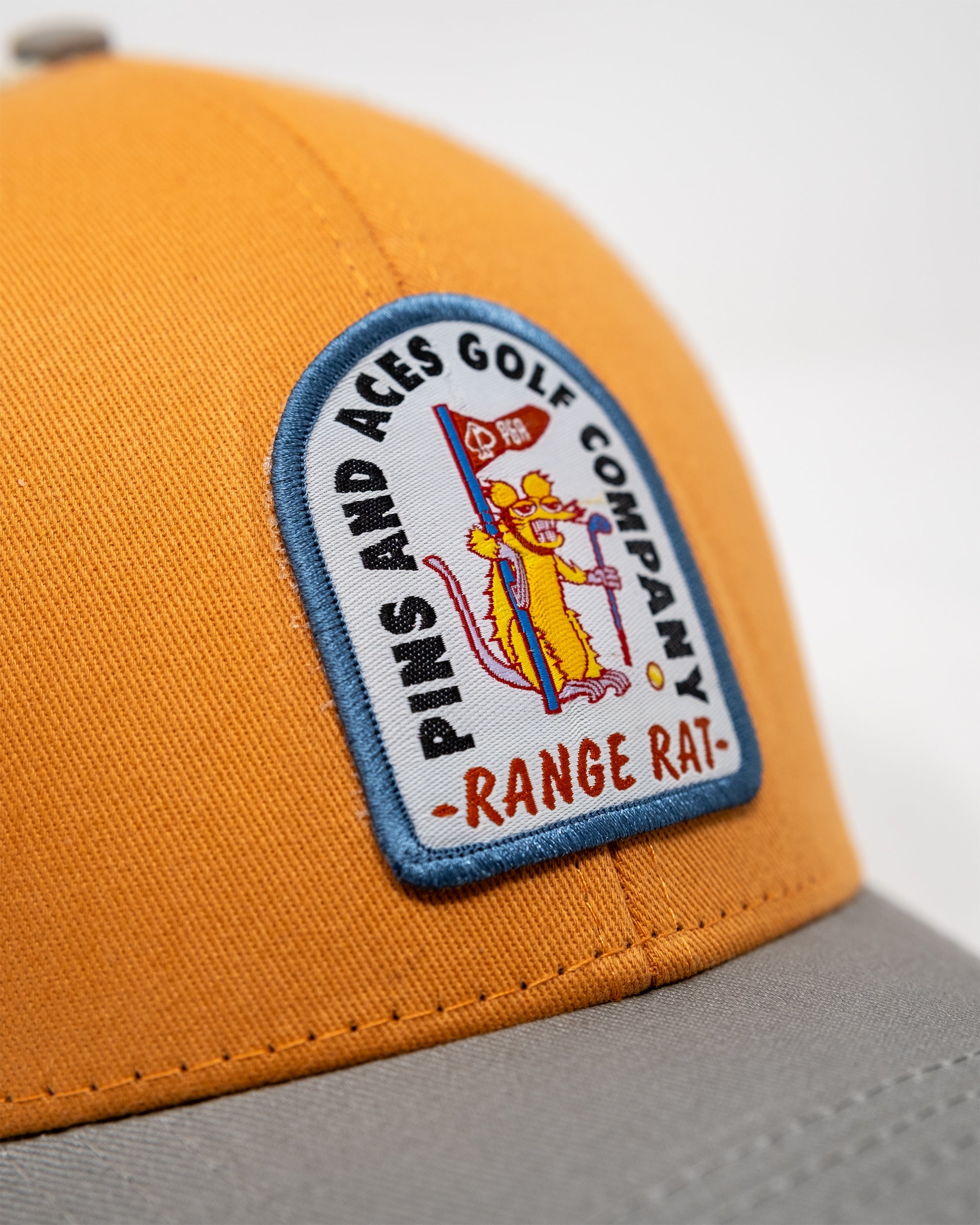 Orange trucker hat featuring "Range Rat" logo, with a mesh back and adjustable snap closure.