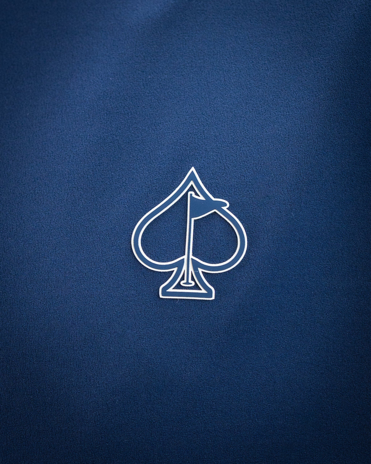 Close-up of a navy blue golf accessory with a white spade and flag logo, highlighting bold, unique design for standout gol...