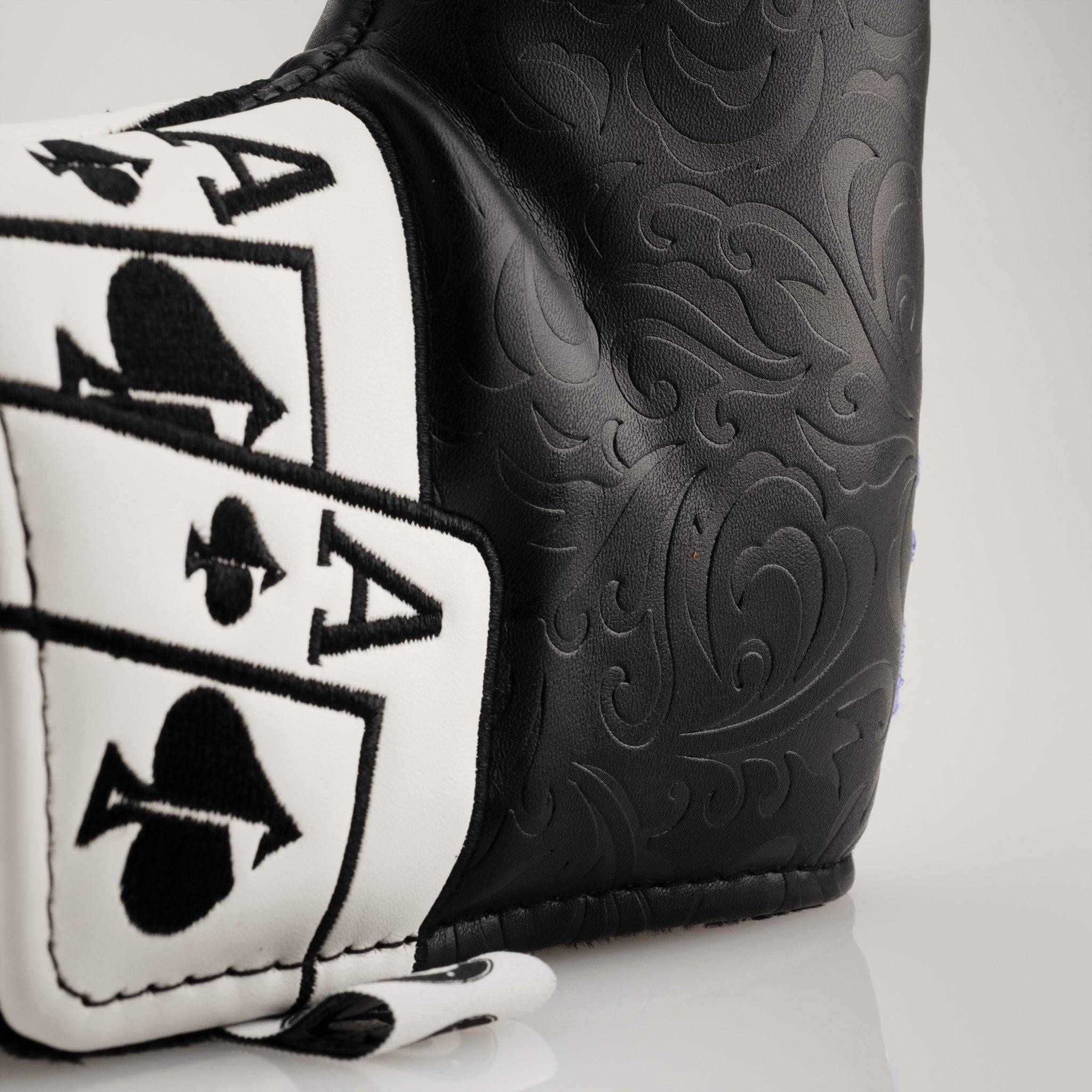 Close-up image of an Ace of Spades blade putter cover, featuring intricate embossed patterns on black faux leather with a prominent black and white Ace of Spades card design.