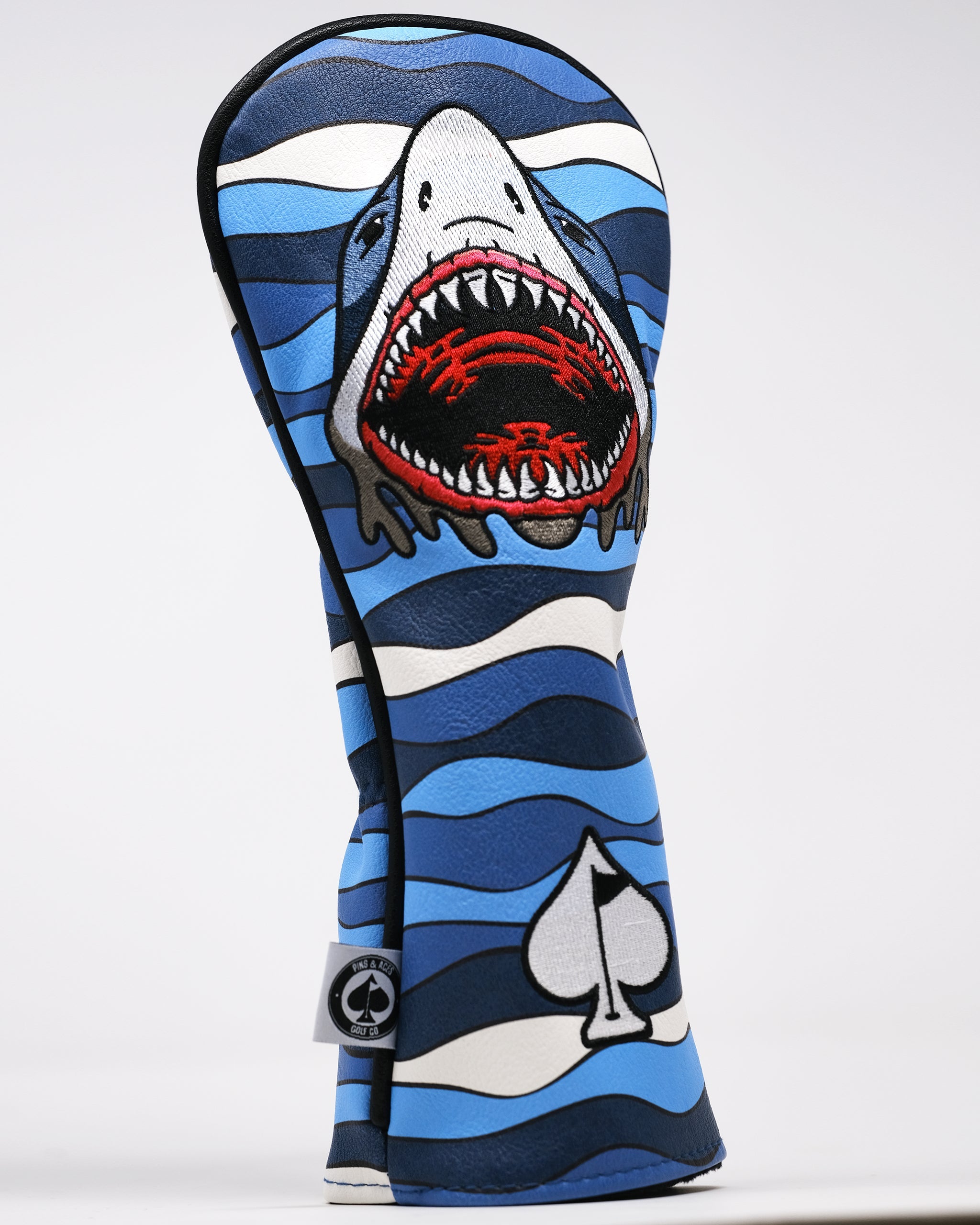 Bold blue golf headcover with a fierce shark design, featuring red accents and a spade logo, perfect for standing out on t...