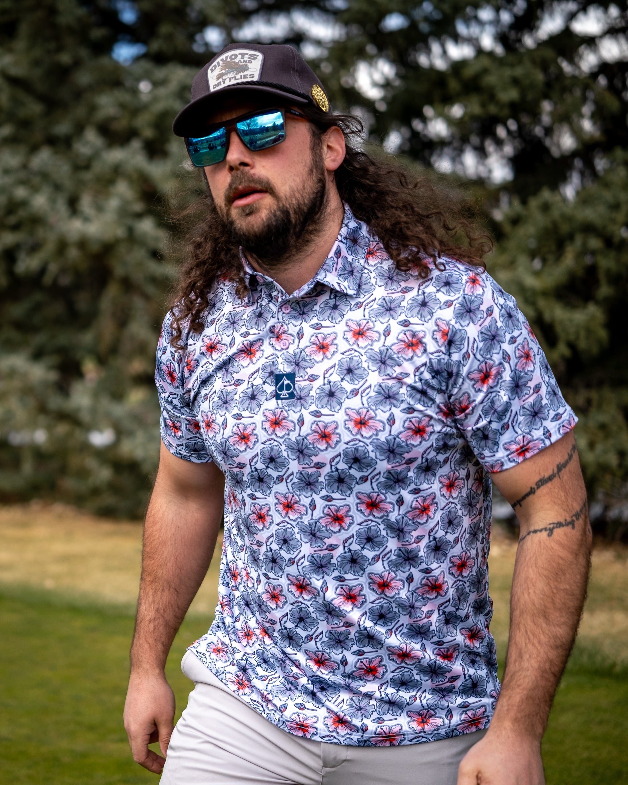 Hibiscus Harmony floral arrangement in a decorative vase, featuring vibrant red and pink hibiscus flowers, lush green foliage, and soft natural lighting.