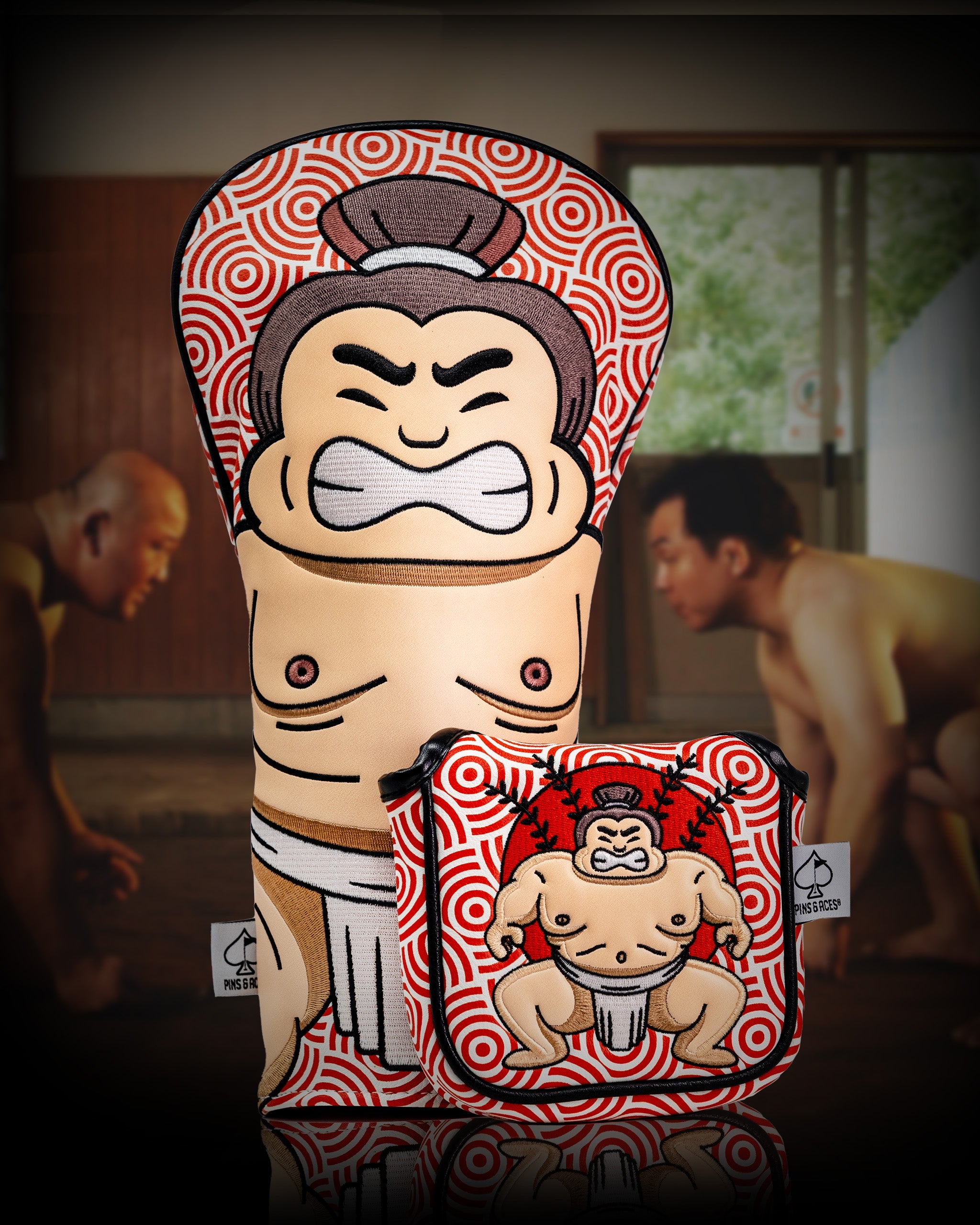 Sumo wrestler-themed mallet putter cover with bold red and white swirl pattern, featuring a cartoon sumo wrestler design.