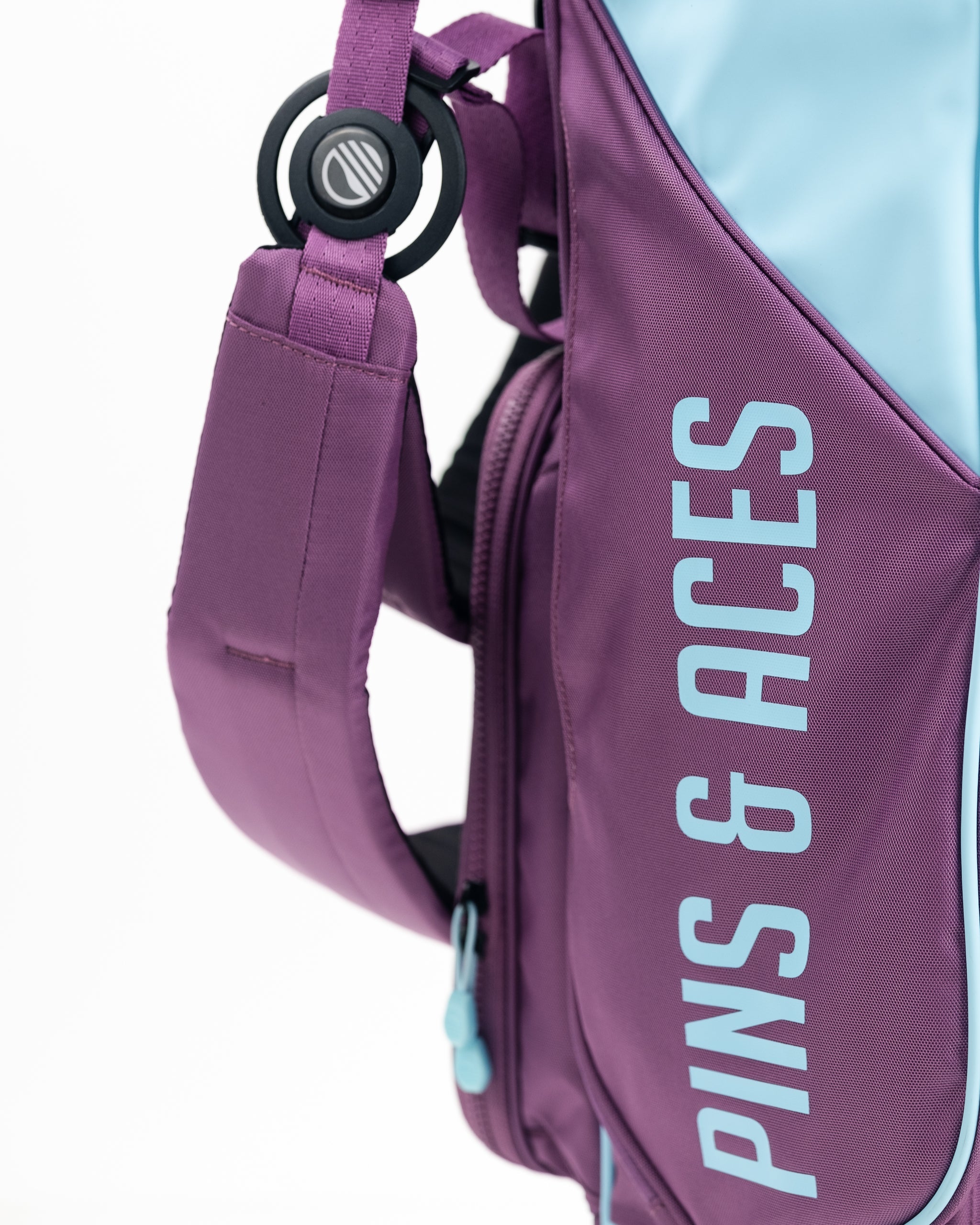 Purple golf bag with light blue accents, bold "PINS & ACCESS" text, and a padded shoulder strap for standout style.