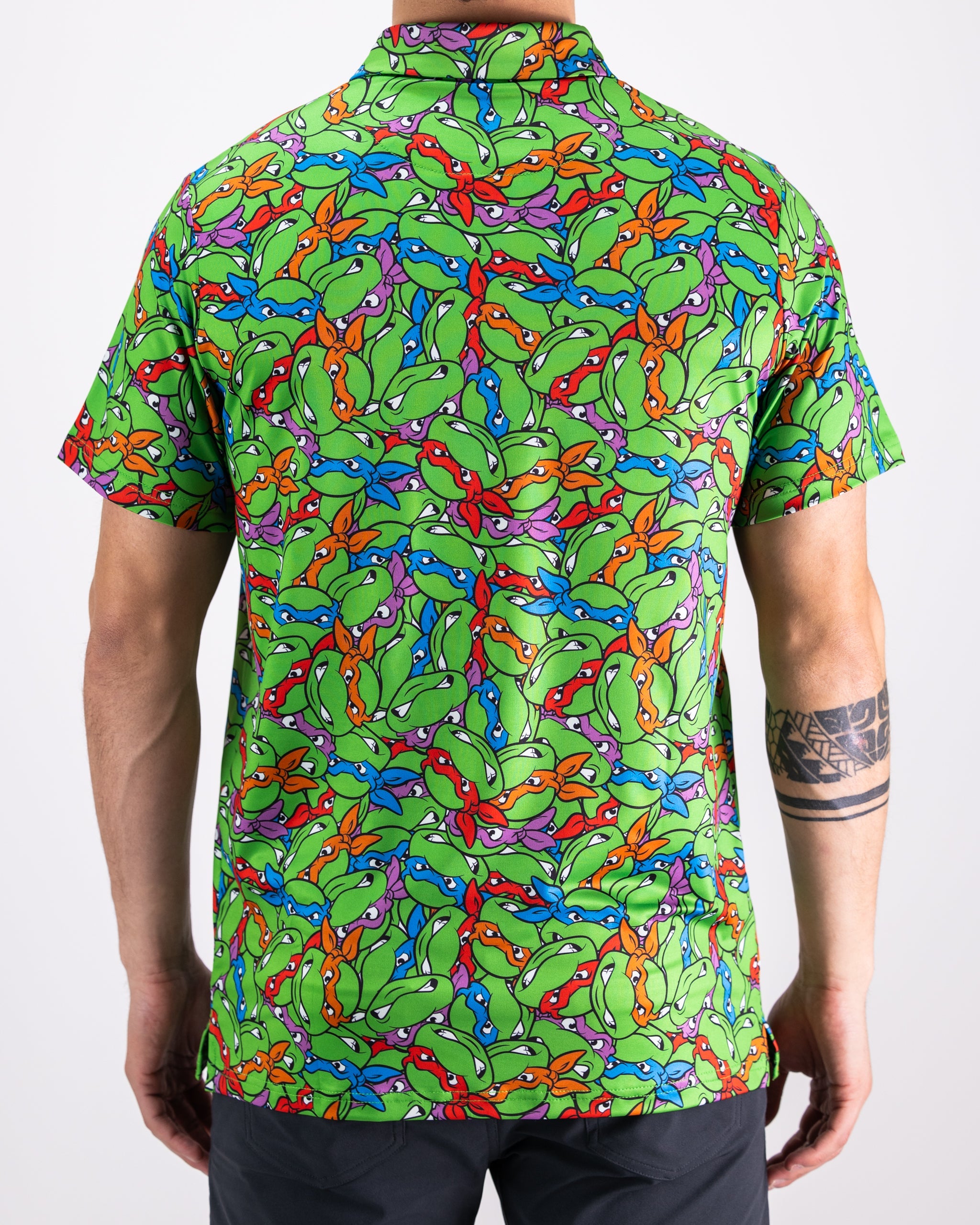 TMNT Mean Green polo shirt featuring colorful turtle head designs on a vibrant green background.