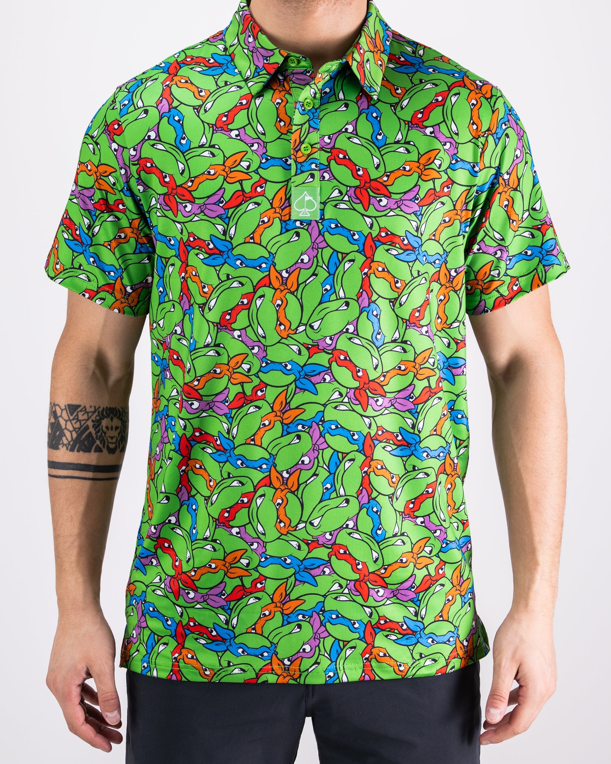 TMNT Mean Green polo shirt featuring colorful turtle head graphics on a vibrant green background.