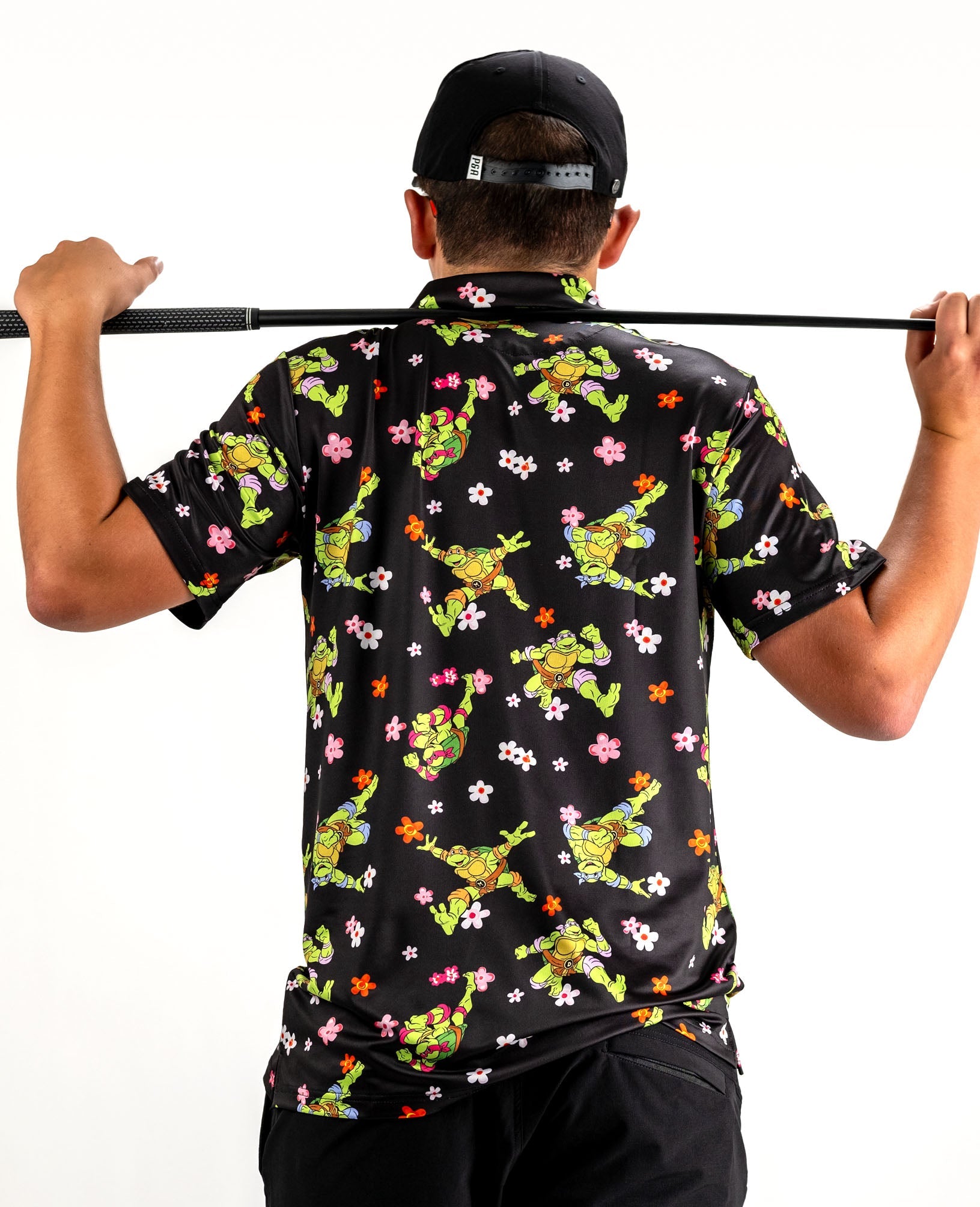 TMNT Turtle Flower Power polo shirt featuring colorful Turtles and floral graphics on a light background.