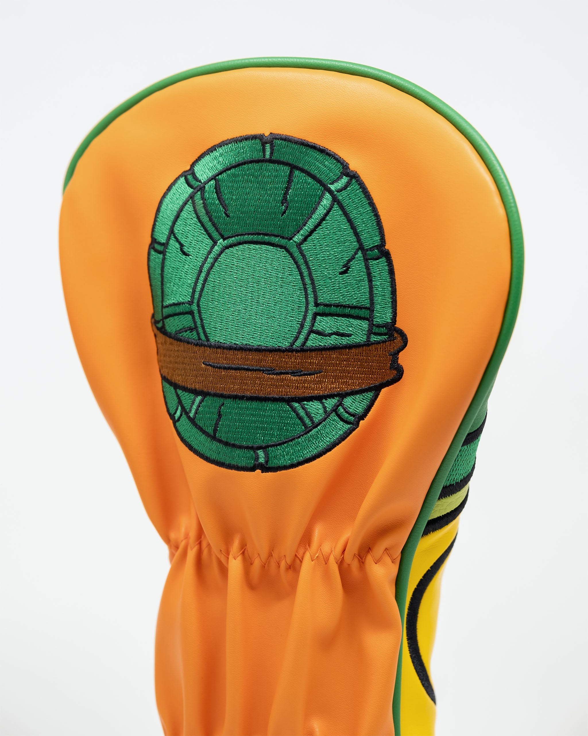TMNT Michelangelo driver cover, featuring vibrant colors and a cartoon-style design of Michelangelo's face with his signature orange mask and nunchaku.