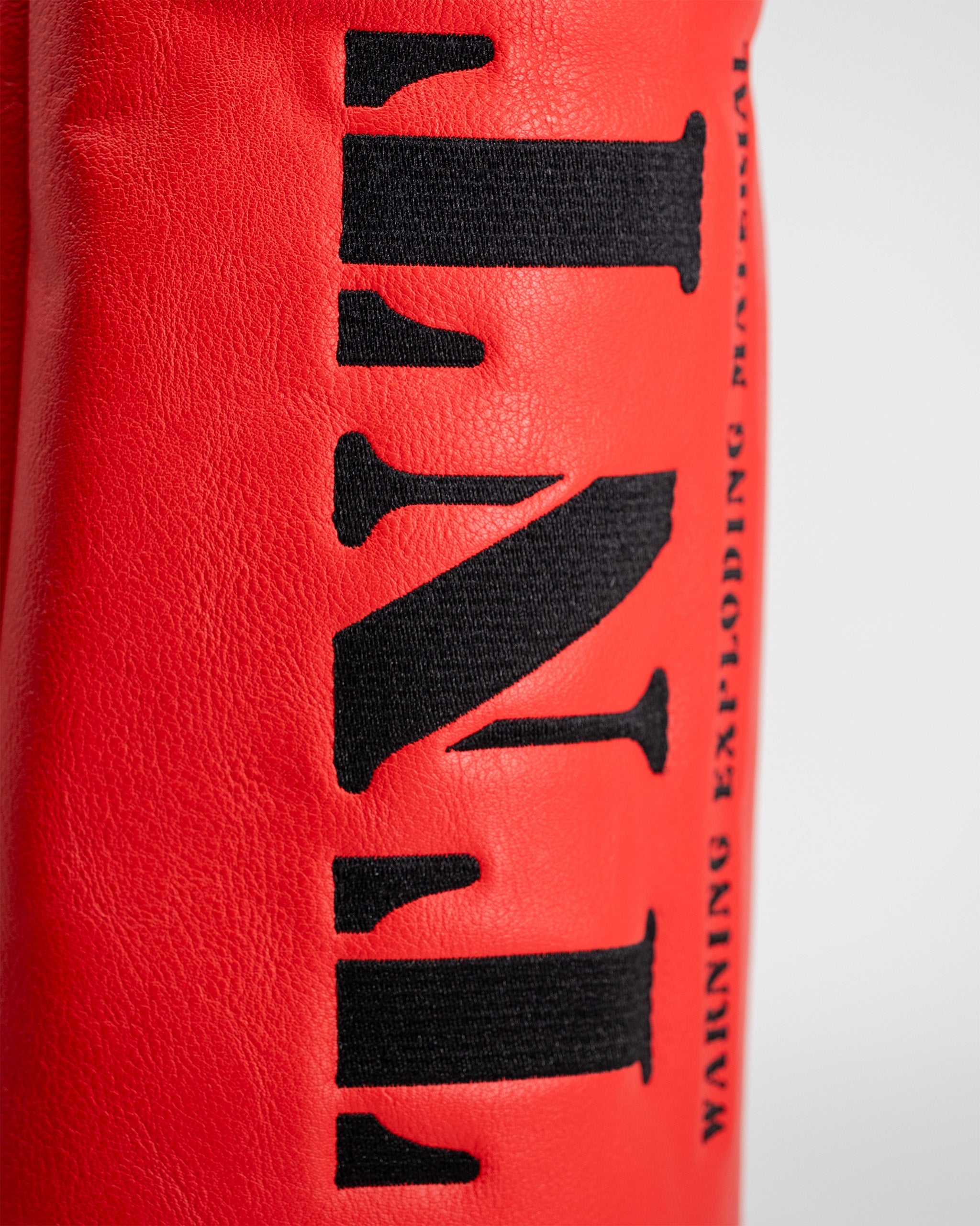 Close-up of a red driver cover with black embroidered text reading "TNT" and additional branding details.
