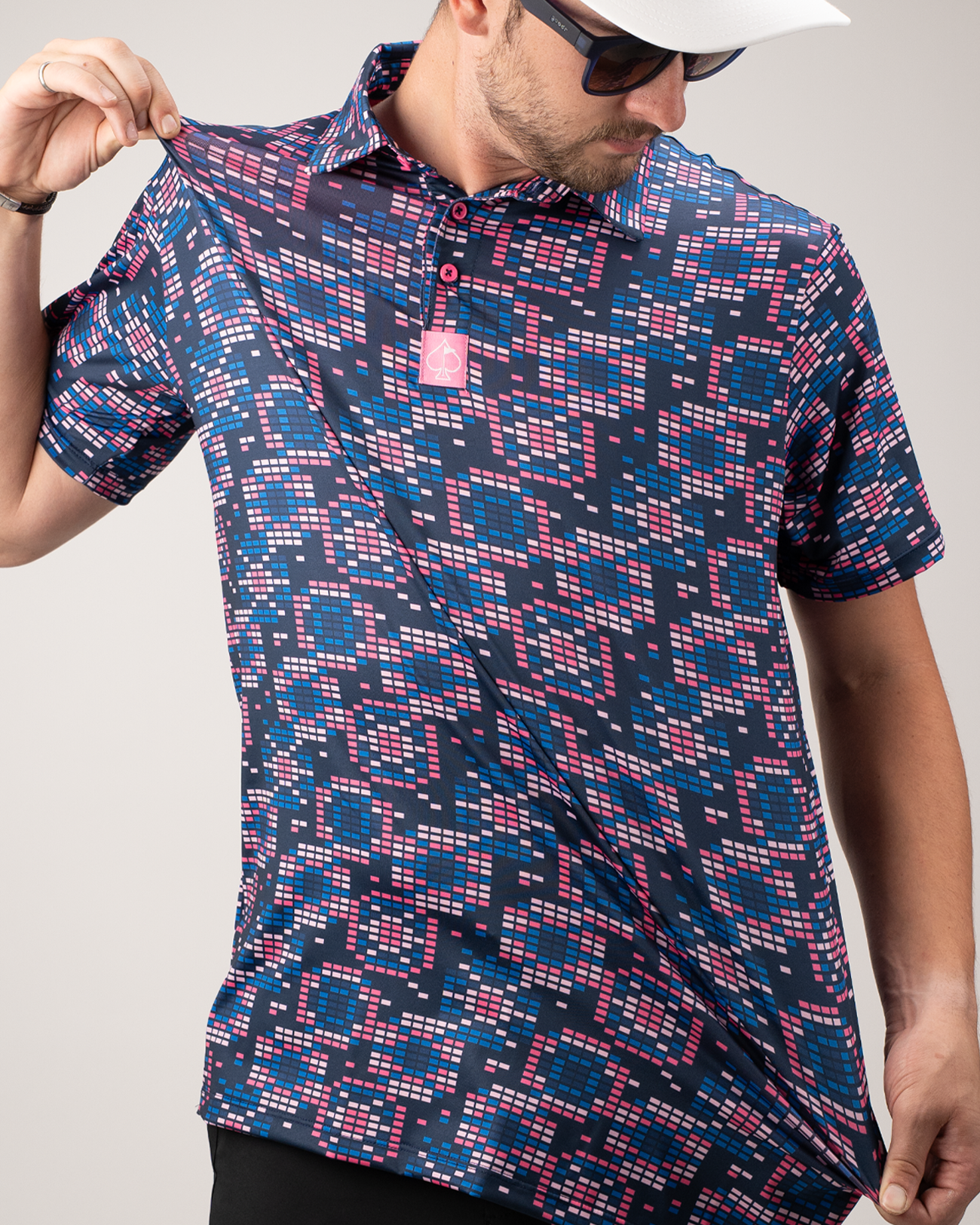 Man wearing a Tetrafloral Dark golf polo shirt featuring a vibrant geometric pattern in navy, pink, and blue.