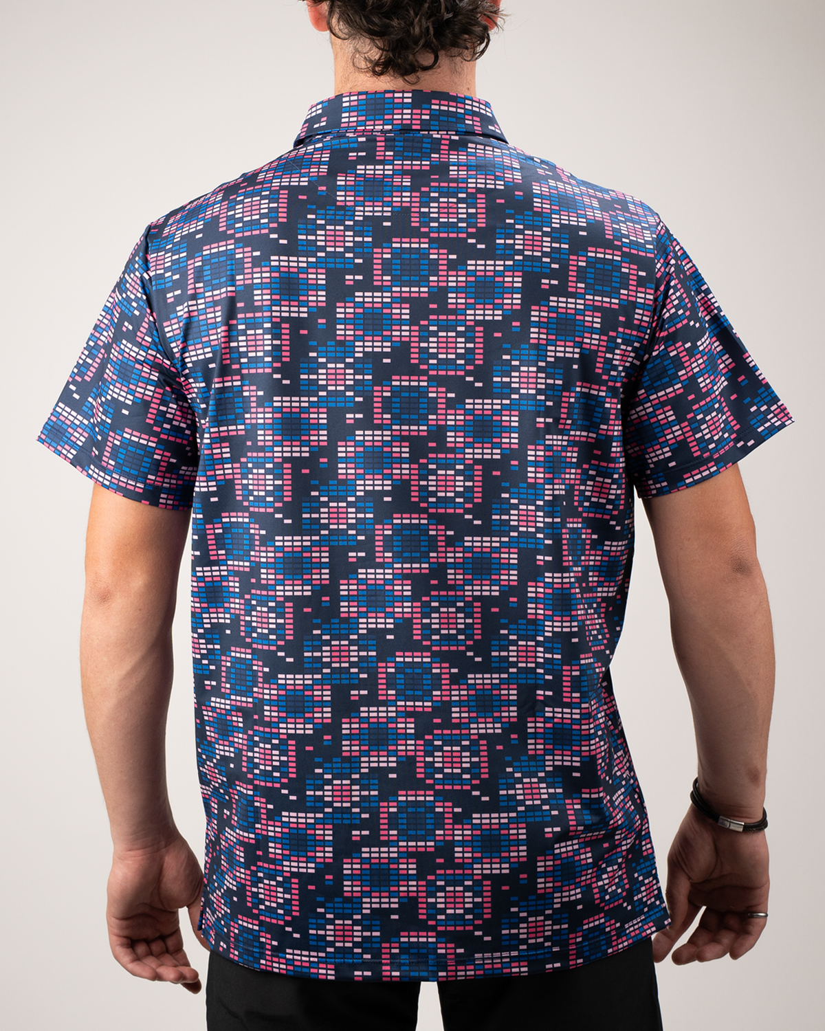 Men's Tetrafloral Dark golf shirt featuring a vibrant geometric pattern in navy, pink, and teal, viewed from the back.