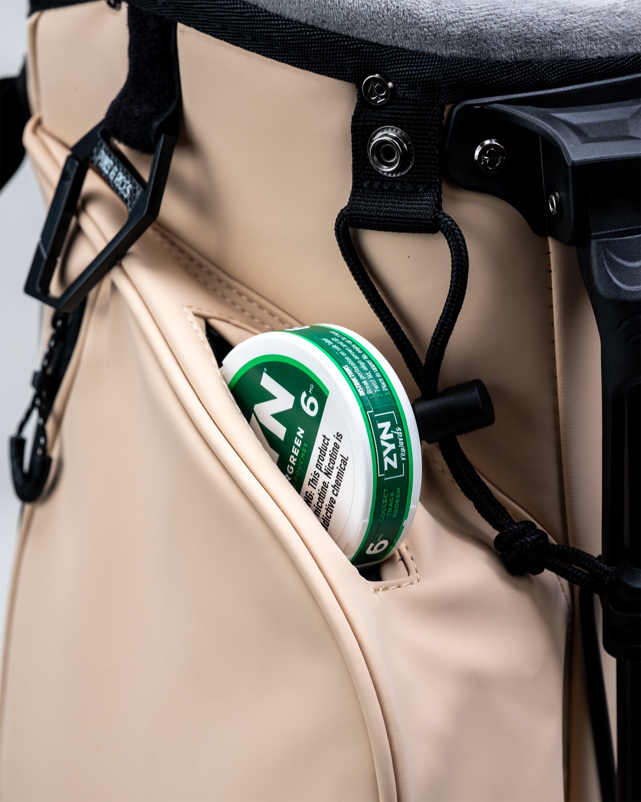 Golf cart with a beige side pocket holding a green and white nicotine gum tin, part of bold golf accessories for standout ...