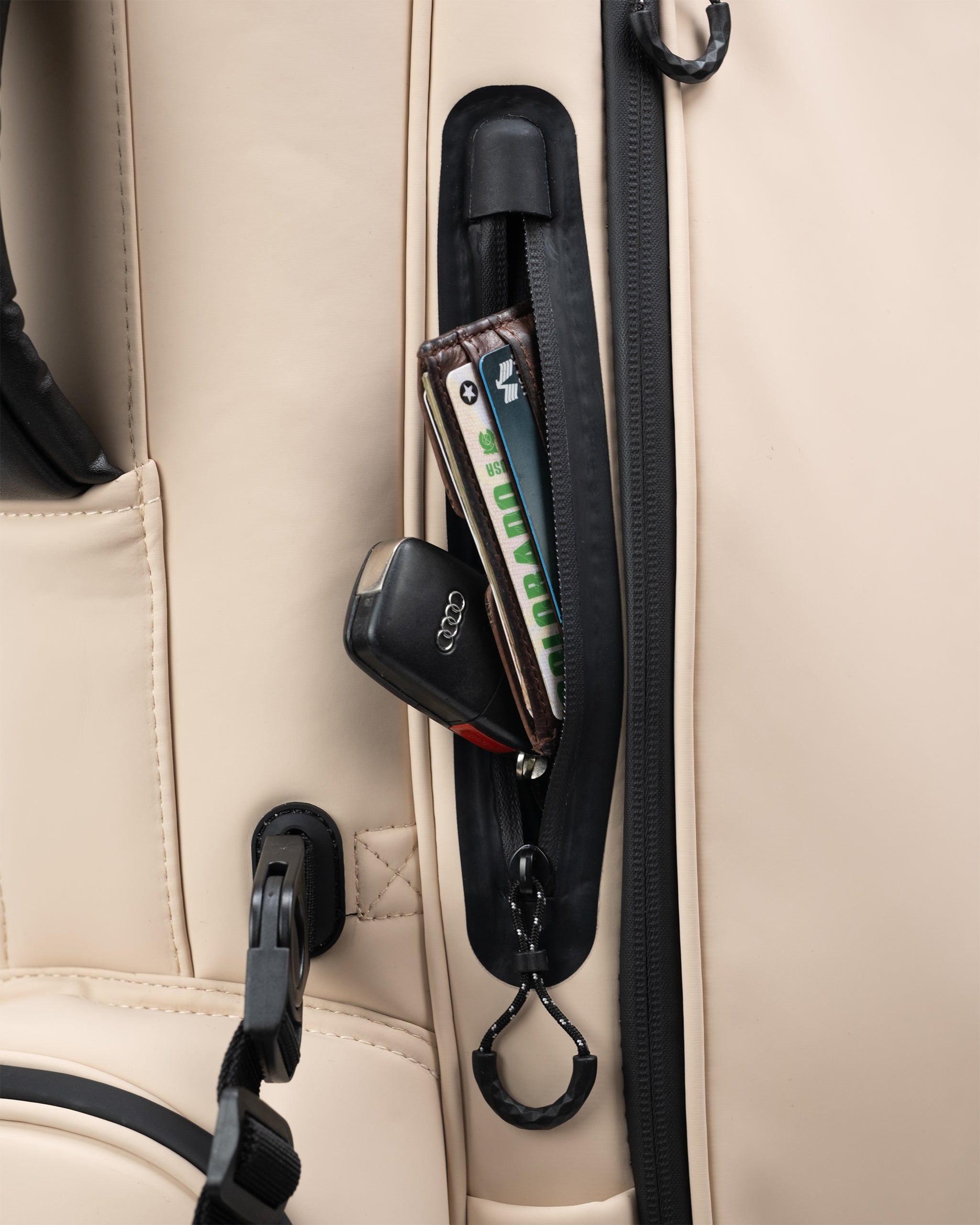 Black zippered golf headcover pocket with wallet, car key, and accessories on a beige golf bag for bold, standout style.