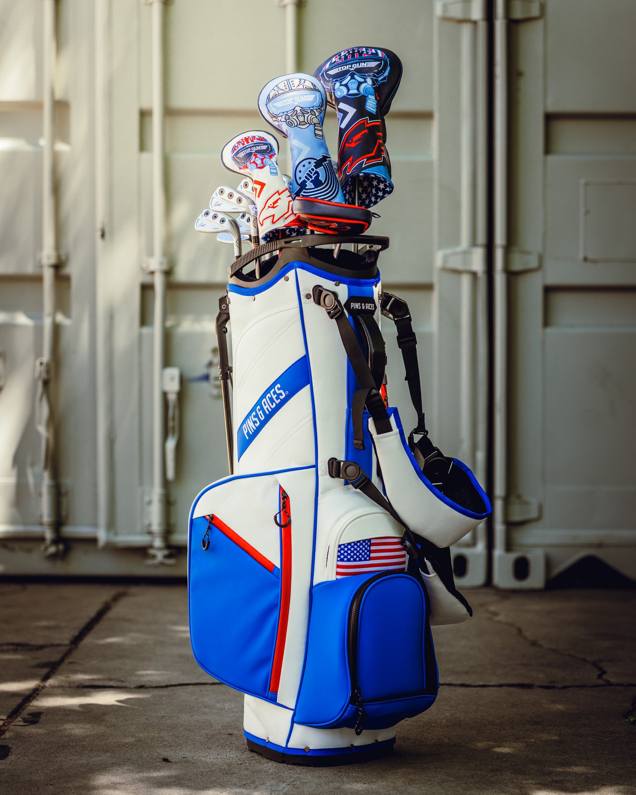 Top Gun Maverick golf driver headcover set on a golf bag, featuring patriotic and fighter jet designs in red, white, blue, and black.