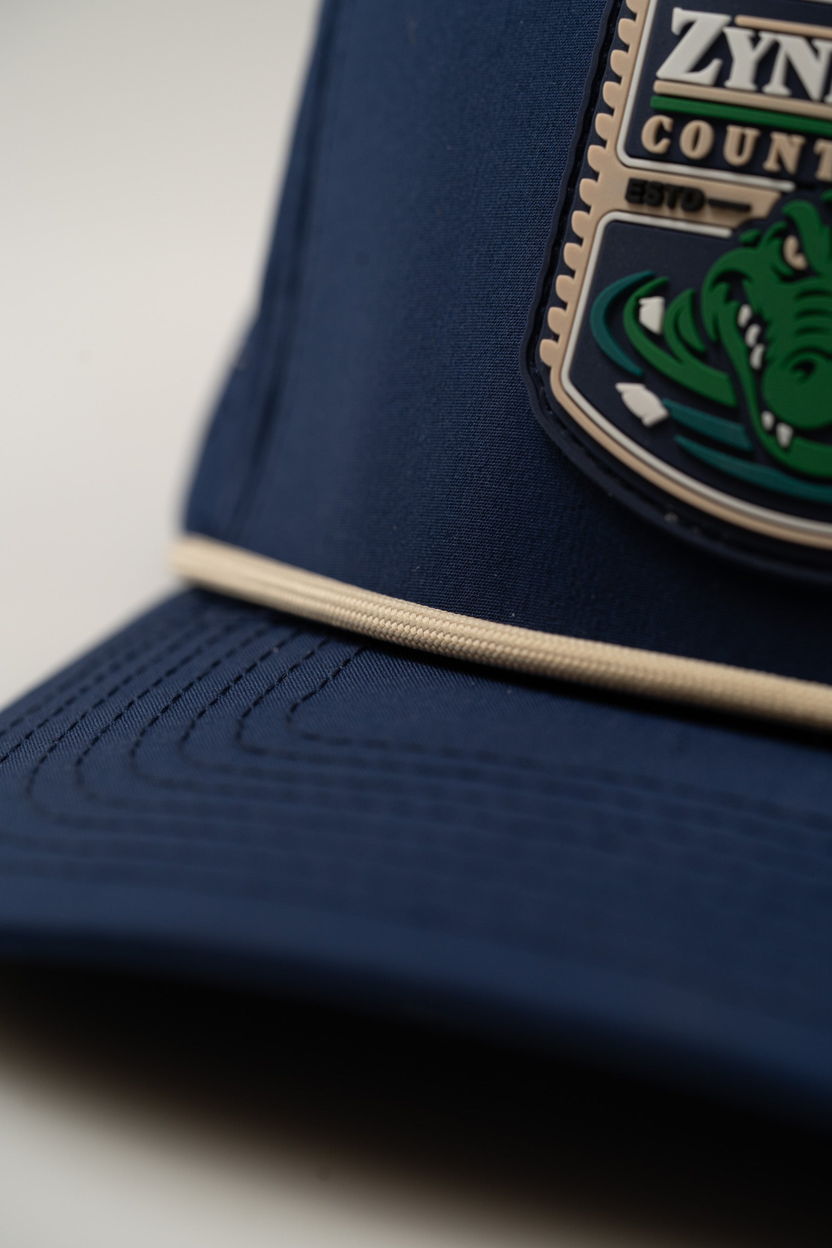Navy perforated rope hat featuring Zynbabwe Country Club logo with a green alligator design. Ideal for stylish golfers.