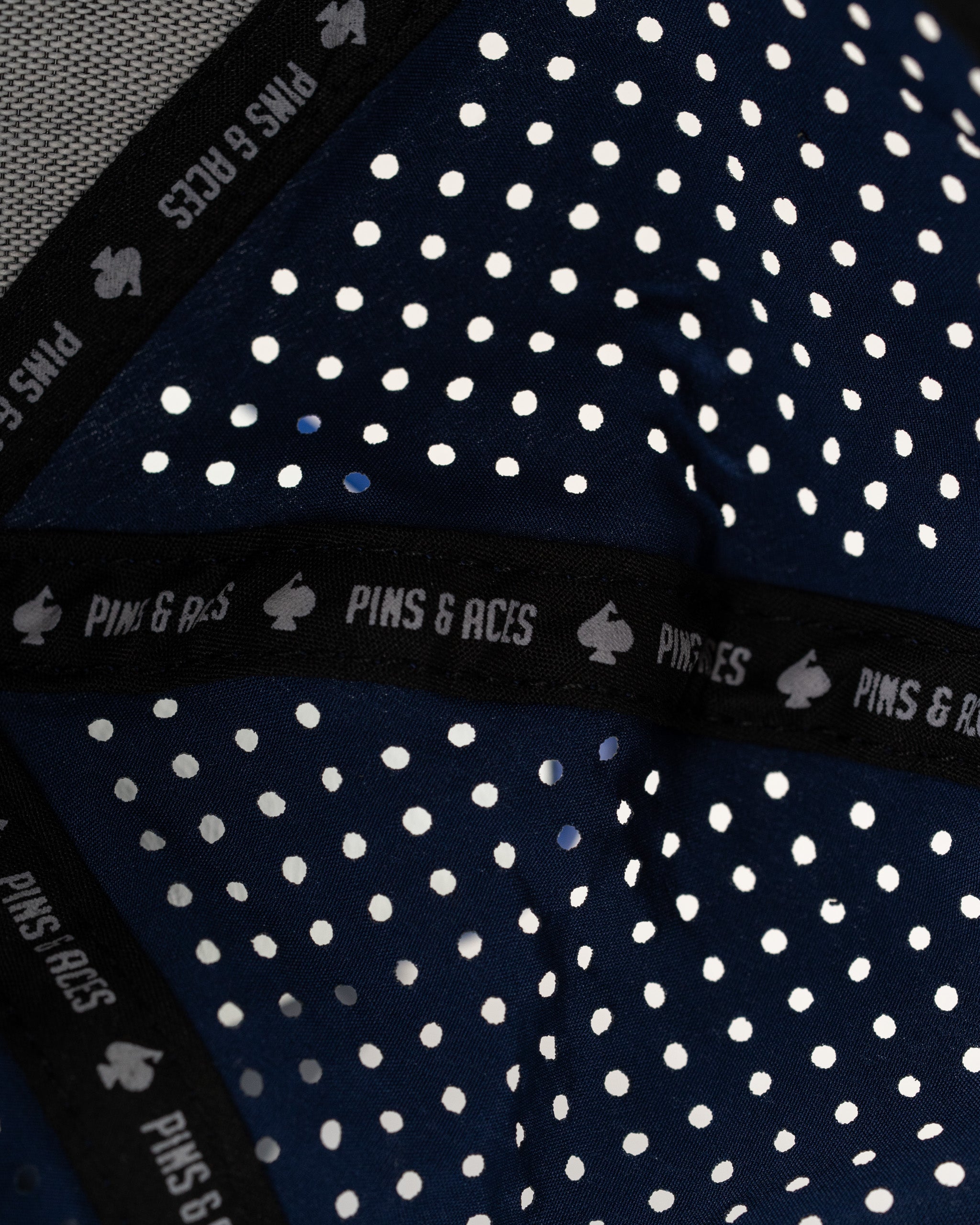 Navy perforated rope hat featuring a stylish design and Pins & Aces branding, perfect for golfers seeking unique apparel.