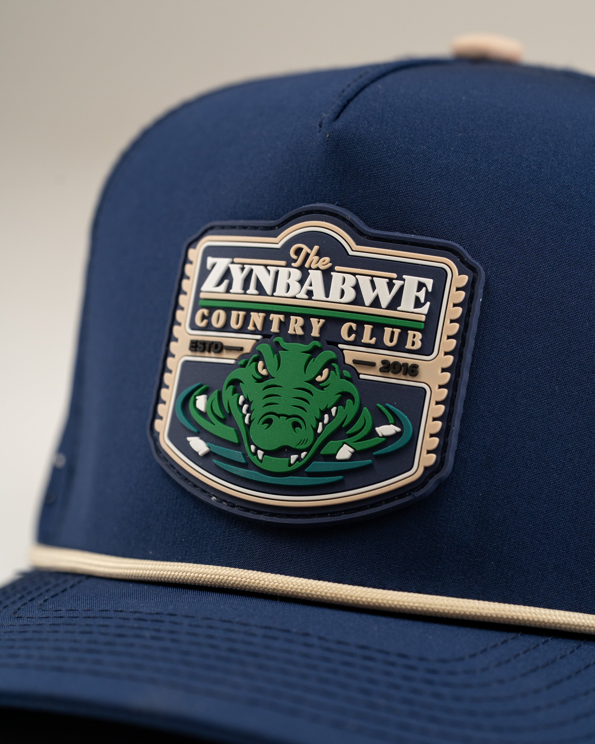 Navy perforated rope hat featuring a Zynbabwe Country Club logo with an alligator design, perfect for stylish golfers.
