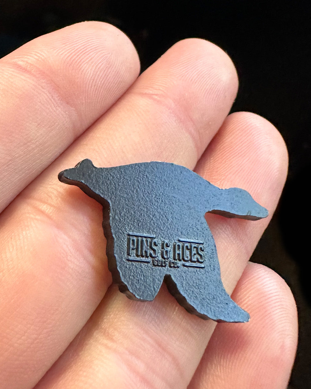 Flying Mallard Ball Marker in hand, featuring a sleek design and Pins & Aces logo, perfect for stylish golfers.