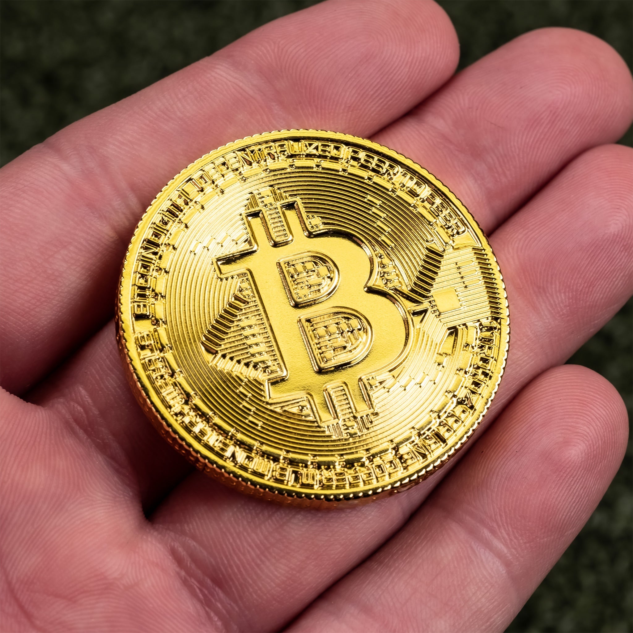 Gold Bitcoin ball marker held in a hand, featuring intricate detailing and the iconic Bitcoin logo for golfers.