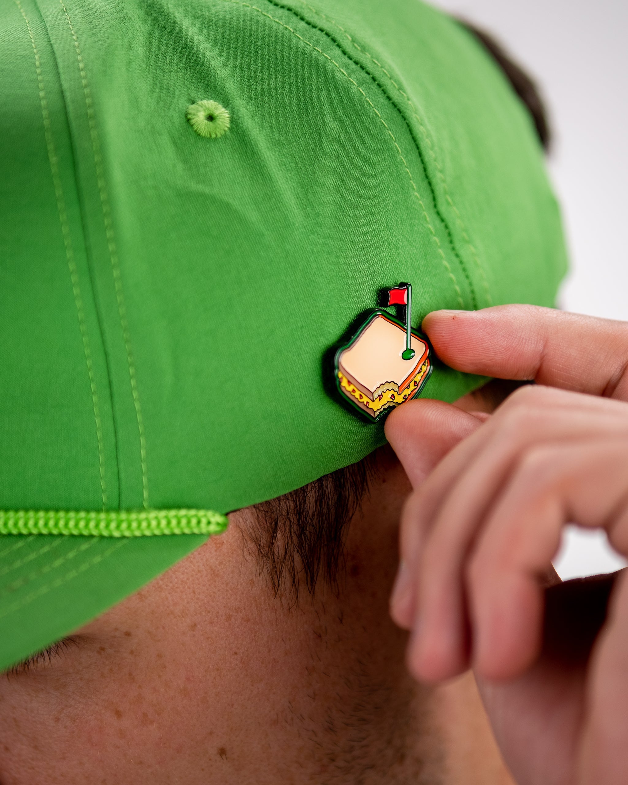 Bright green golf cap with a colorful taco-shaped pin featuring a red flag, ideal for bold golf style.
