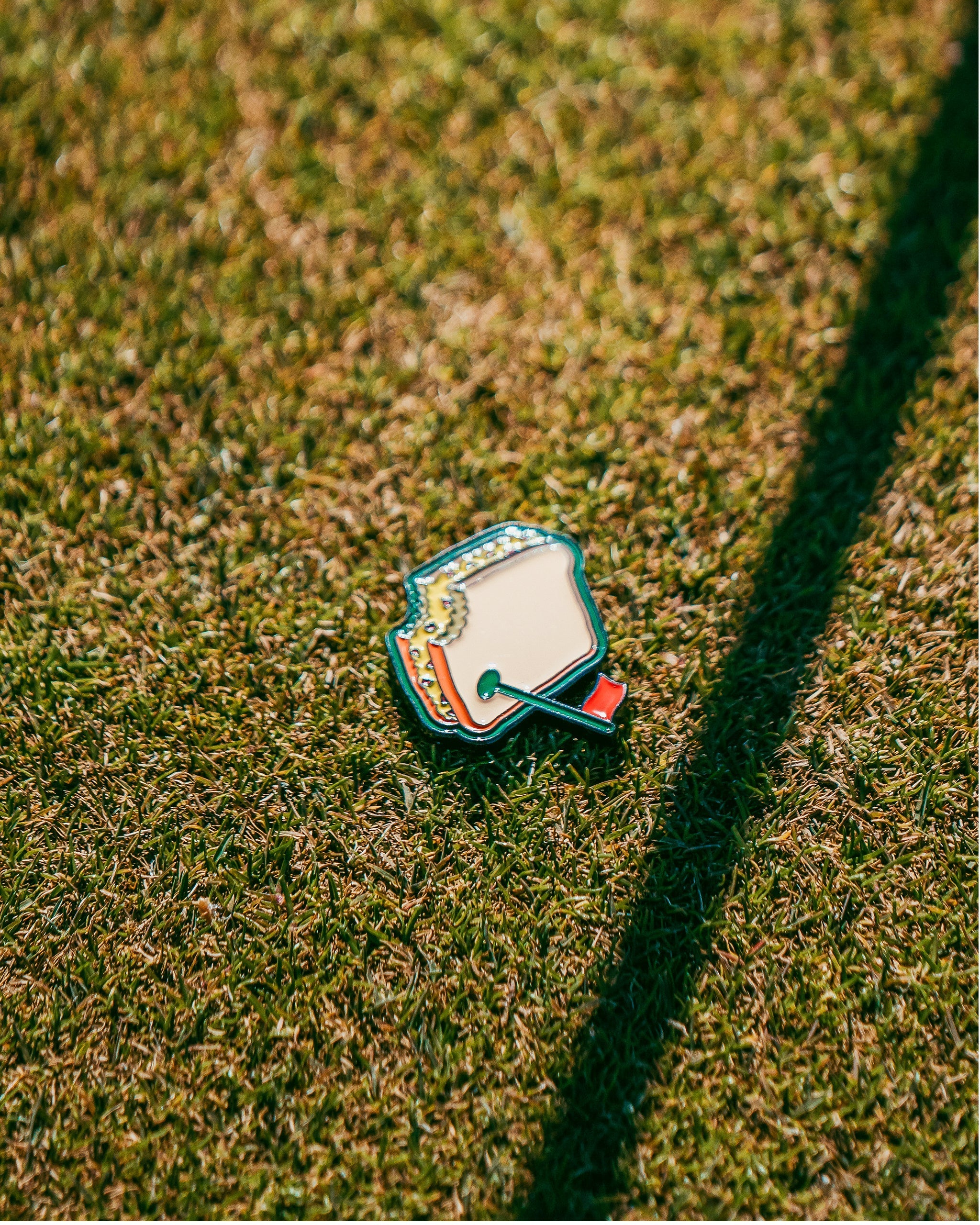 Colorful golf headcover with cartoon design, lying on grass with a shadow, perfect for bold golf style accessories.