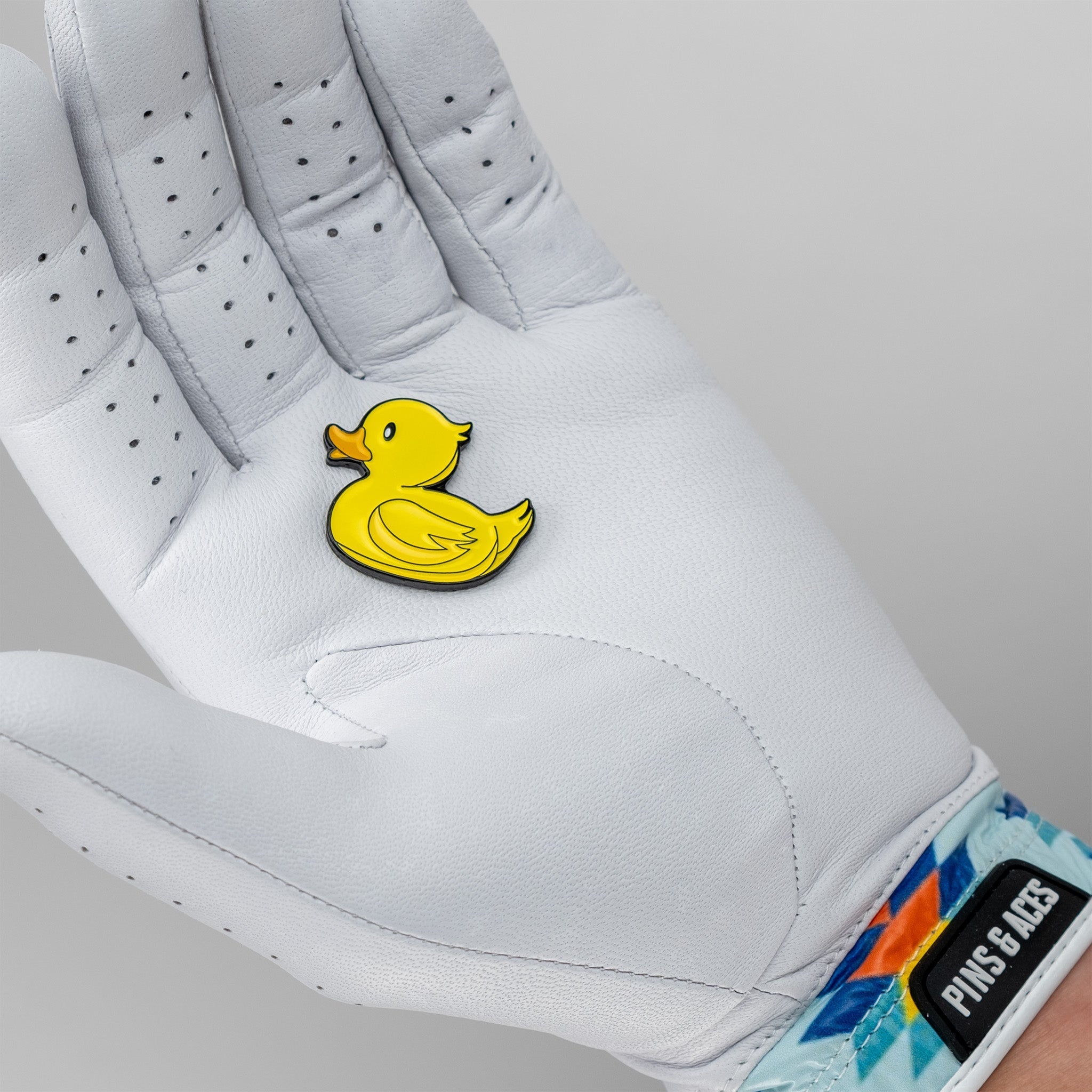 Bright yellow rubber ducky ball marker resting on a golfer's white glove, adding a playful touch to the game.