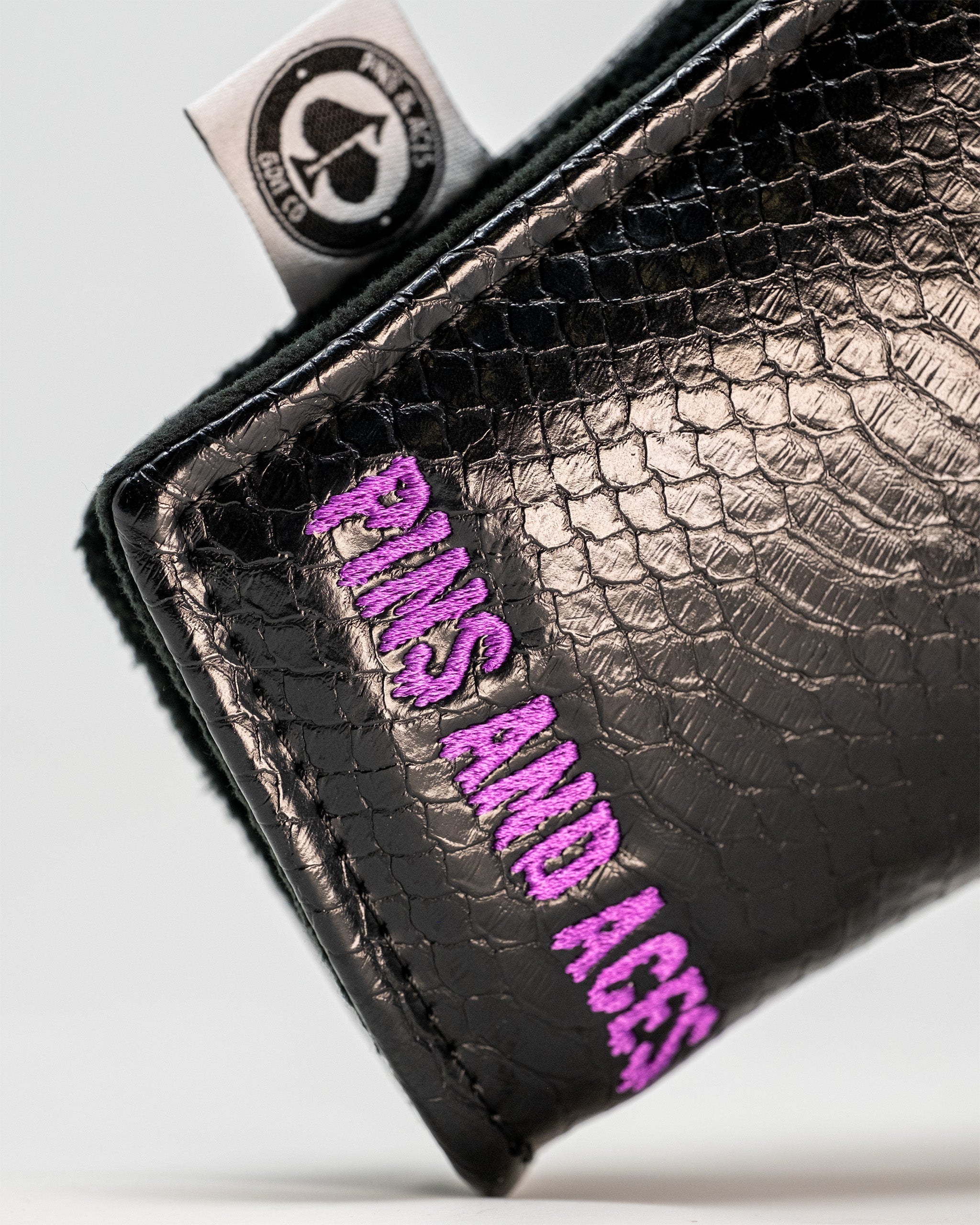 Venom Blade Putter Cover featuring a sleek black design with textured finish and bold purple "Pins and Aces" embroidery.