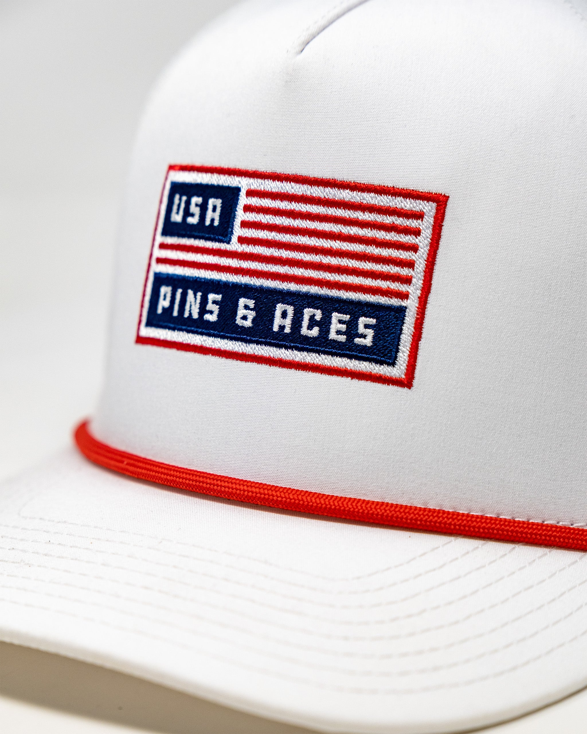 Perforated white rope hat with USA flag embroidery and red trim, featuring the text USA and Pine 6 Races.